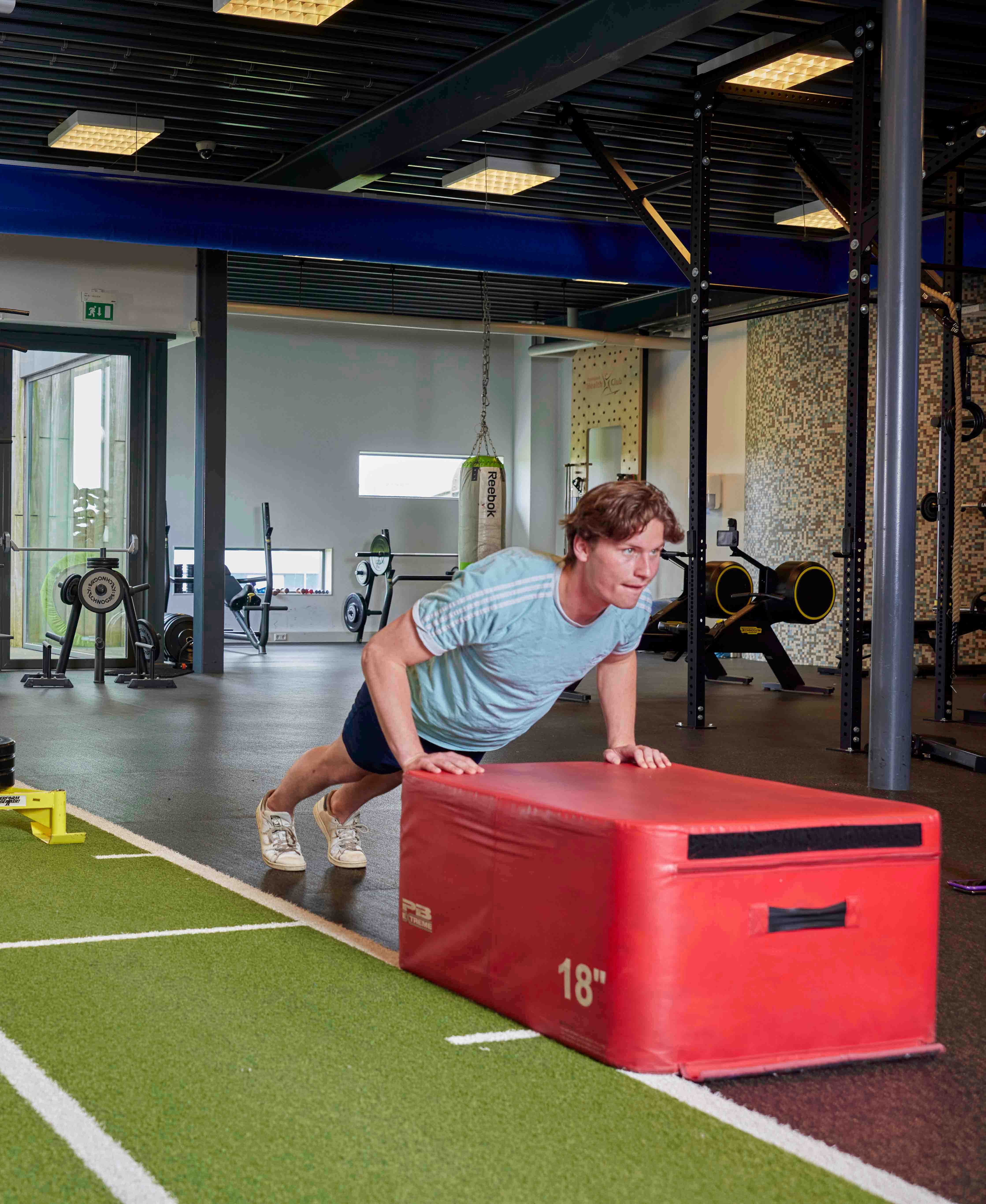 Jongen drukt op tijdens een intensieve workout in de sportschool van Optisport