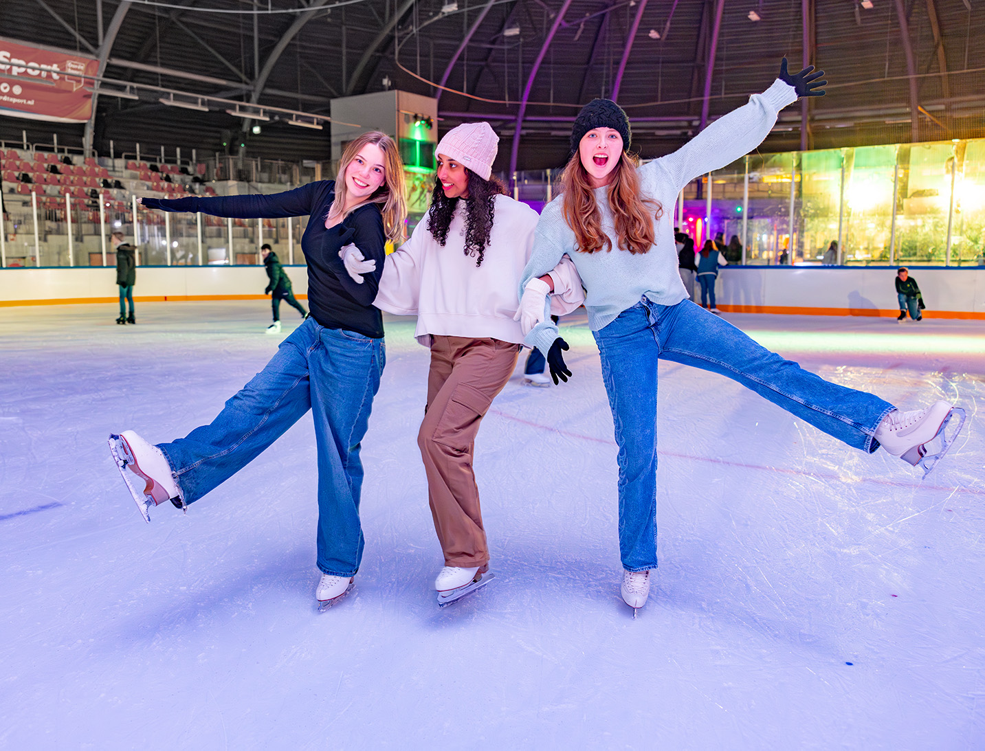 Drie meiden houden elkaar vast op het ijs tijdens het disco schaatsen
