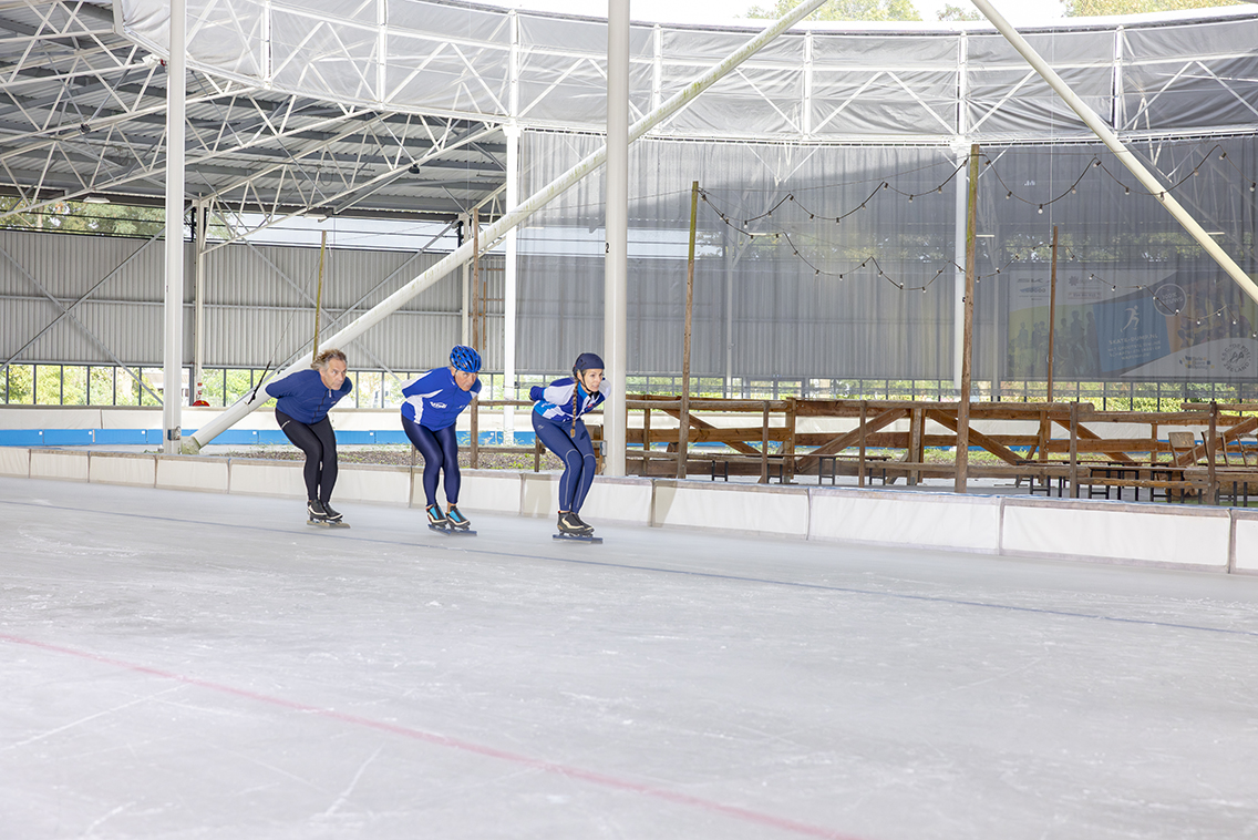 Drie personen schaatsen op eigen tempo in een treintje rondjes tijdens de Buffelavond bij een Optisport schaatsbaan