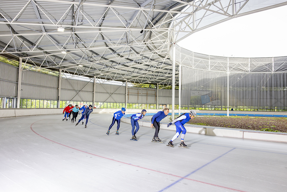 Een groep schaatst in een treintje rondjes tijdens de Buffelavond bij een Optisport schaatsbaan