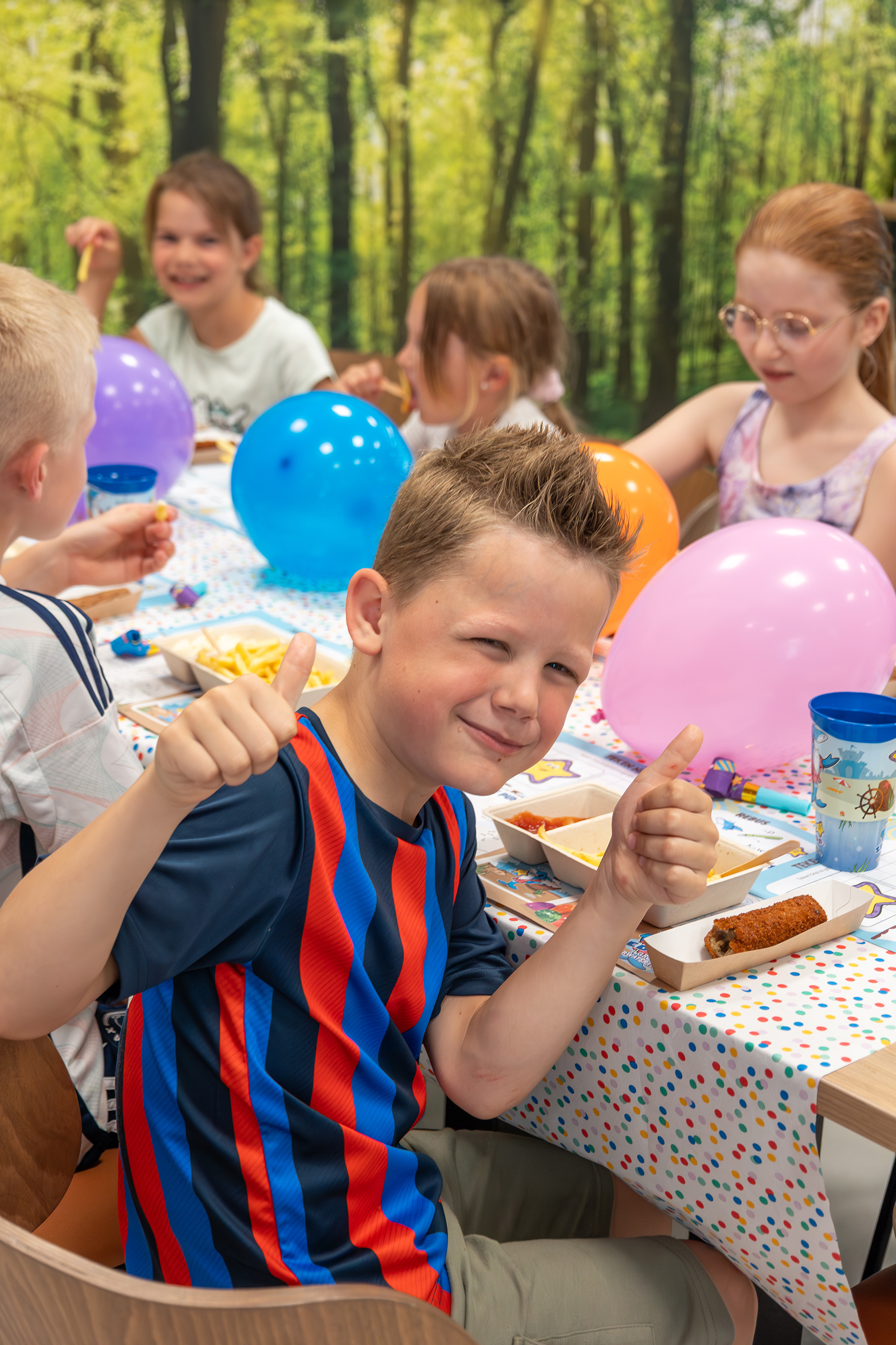 Jongetje zit te eten en steekt duimen op