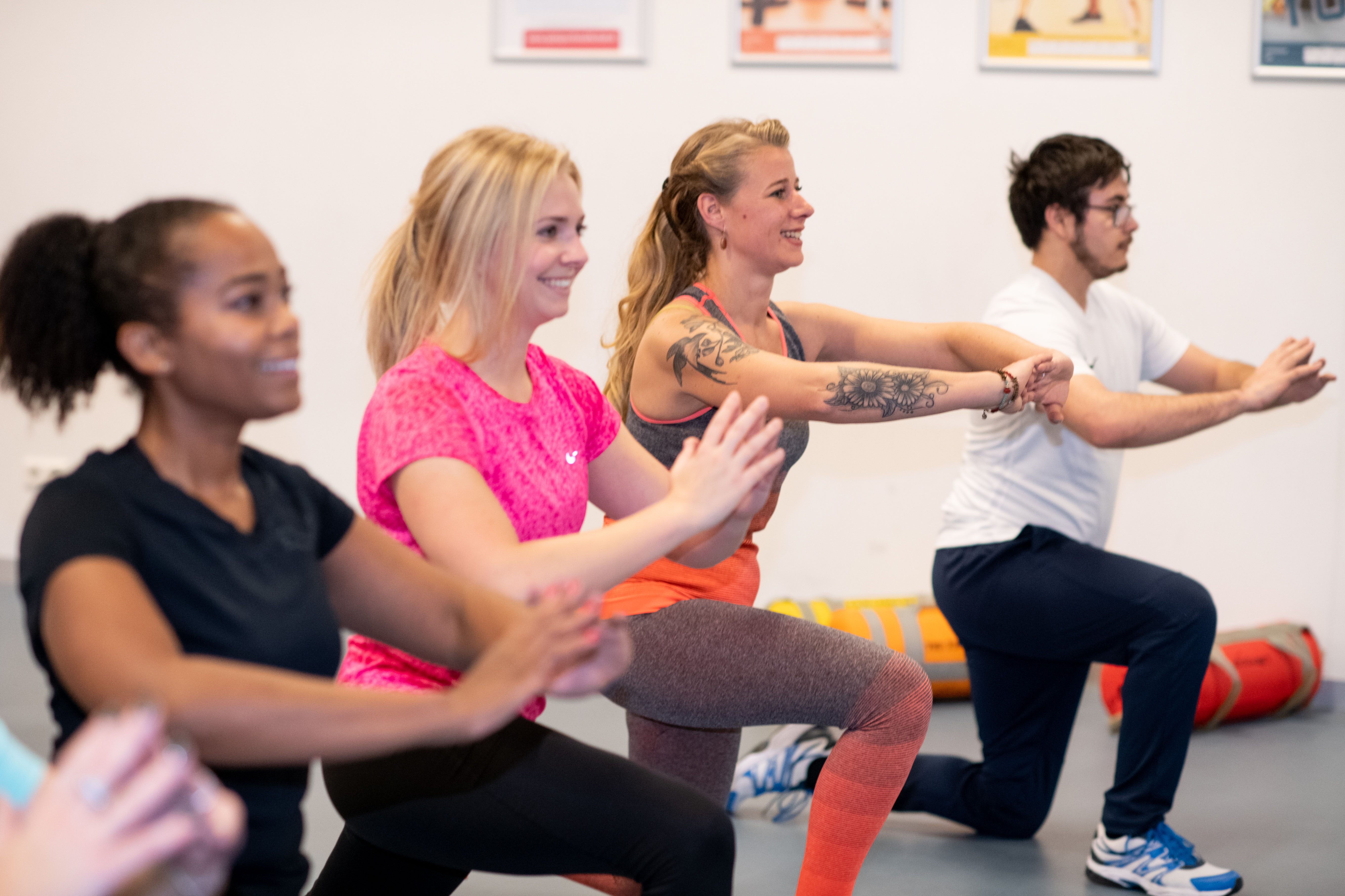 Drie vrouwen doen oefeningen met een bal en hebben plezier tijdens het trainen bij een Optisport locatie