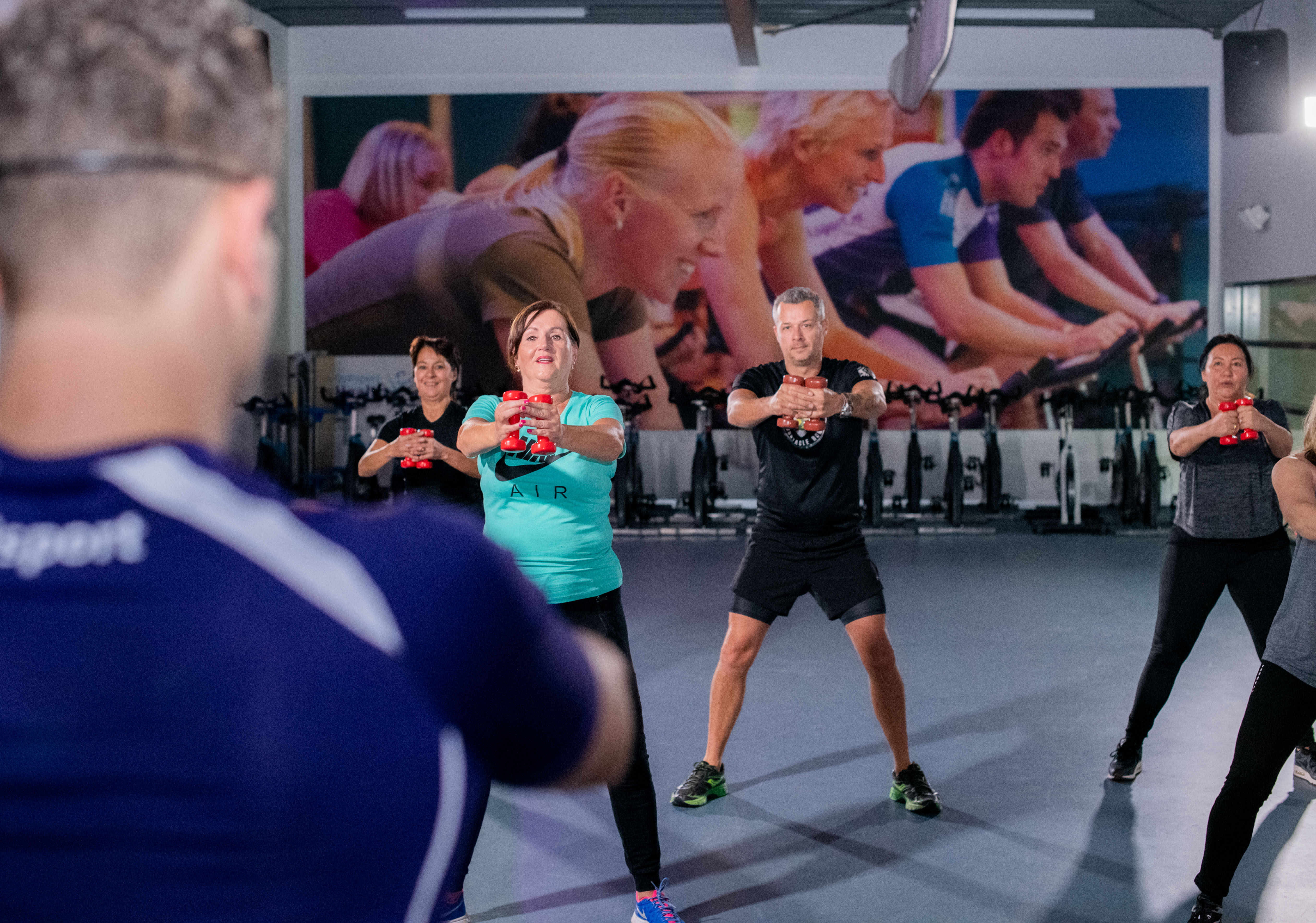 Workout voor vijftigplussers gericht op conditie, kracht en lenigheid. Groep mensen doen verschillende oefeningen.