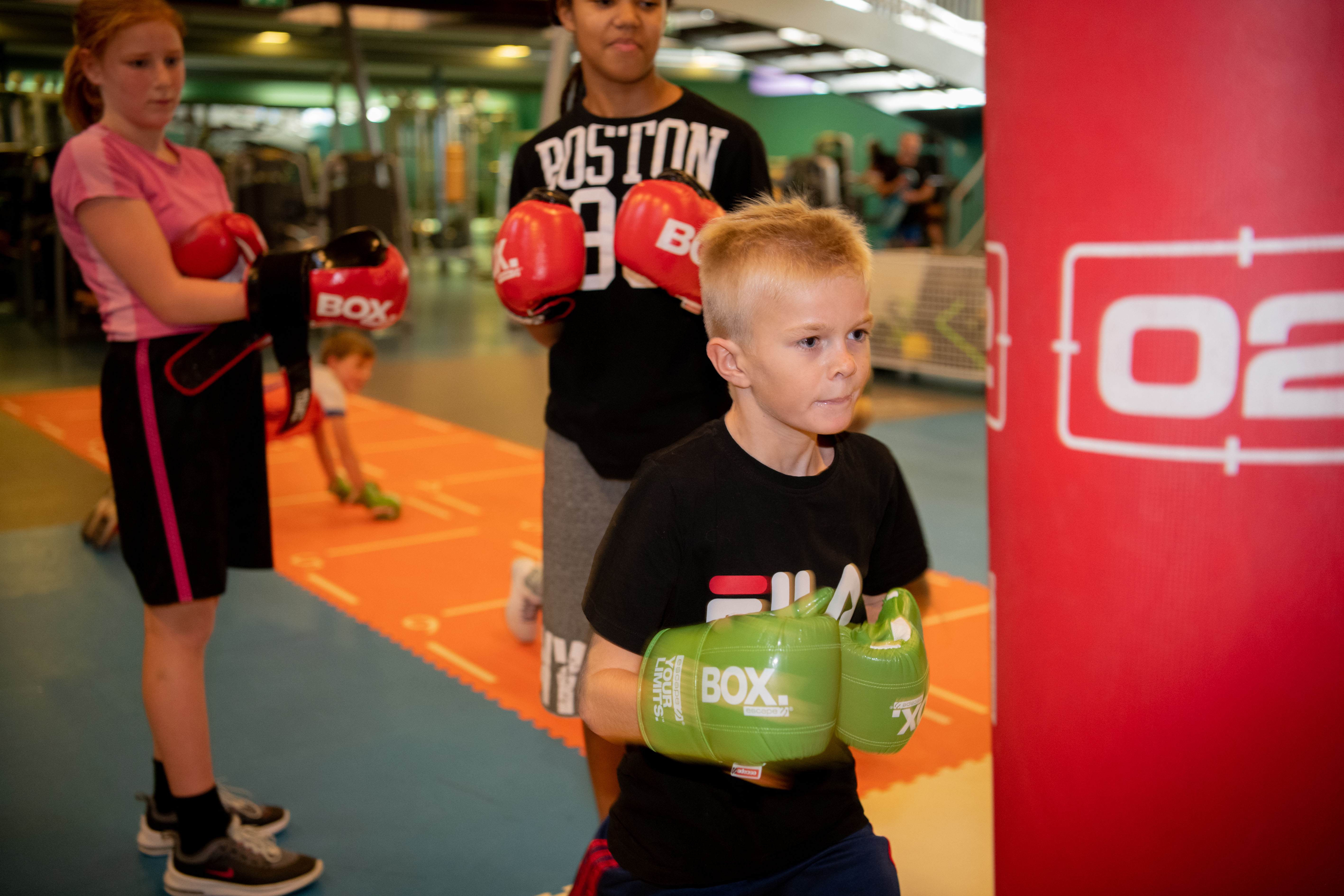 Kinderen zijn aan het boksen zonder lichamelijk contact. Tijdens een groepsles hebben de kinderen plezier onder begeleiding van een instructeur van Optisport.