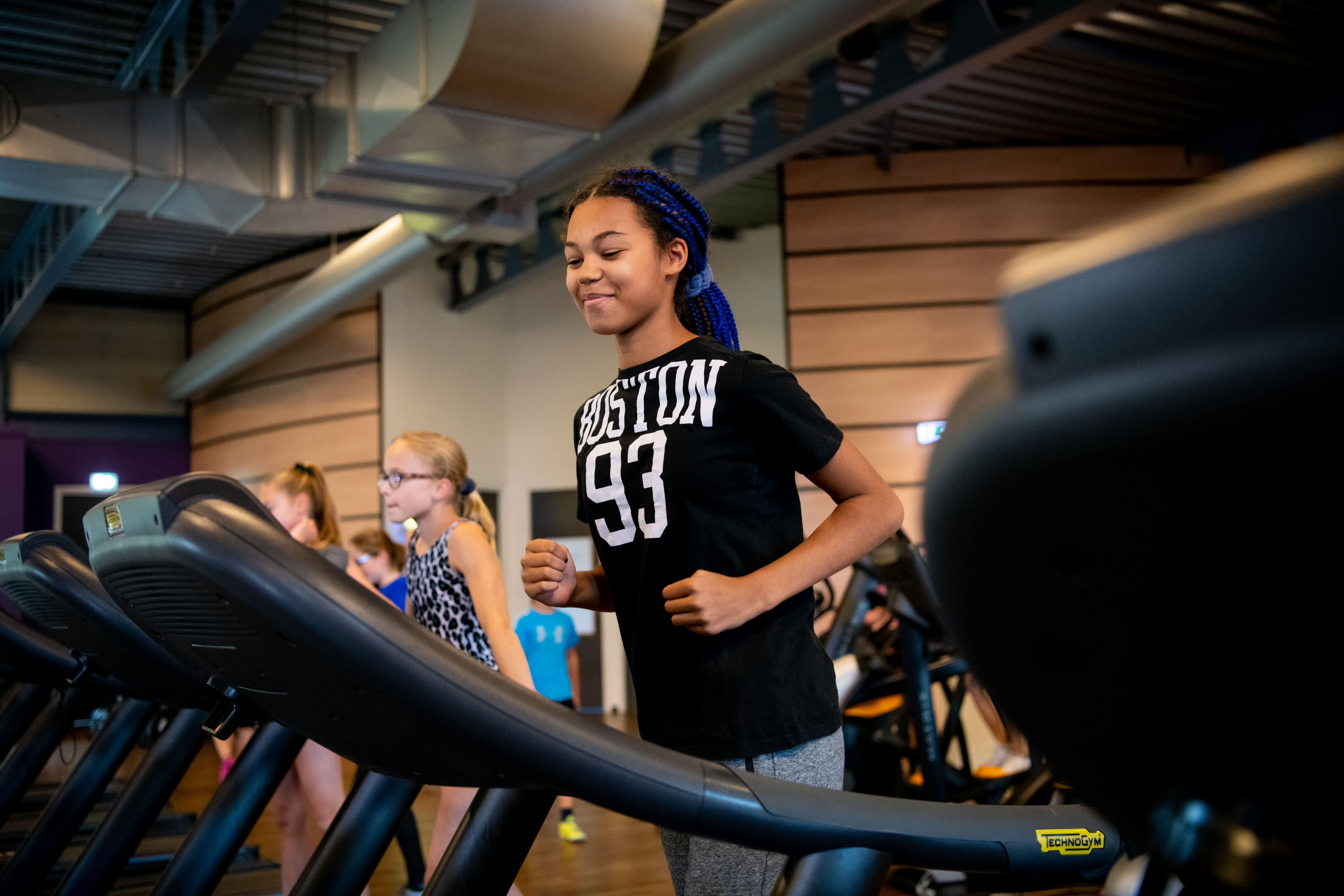 Een meisje is aan het hardlopen op een loopband in de sportschool.