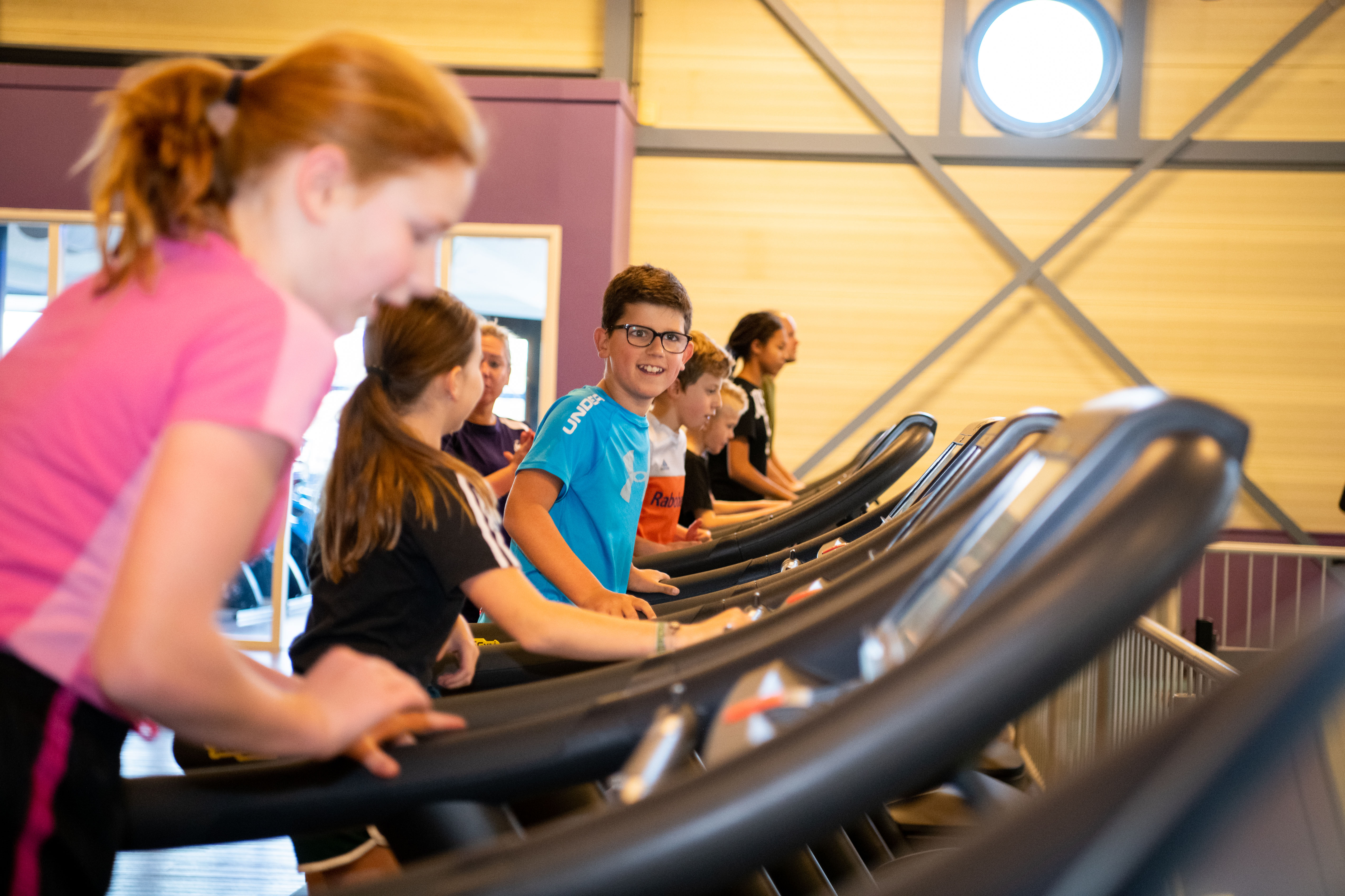 Kinderen zijn onder begeleiding van een instructeur op de loopband aan het sporten om een goede conditie te krijgen.