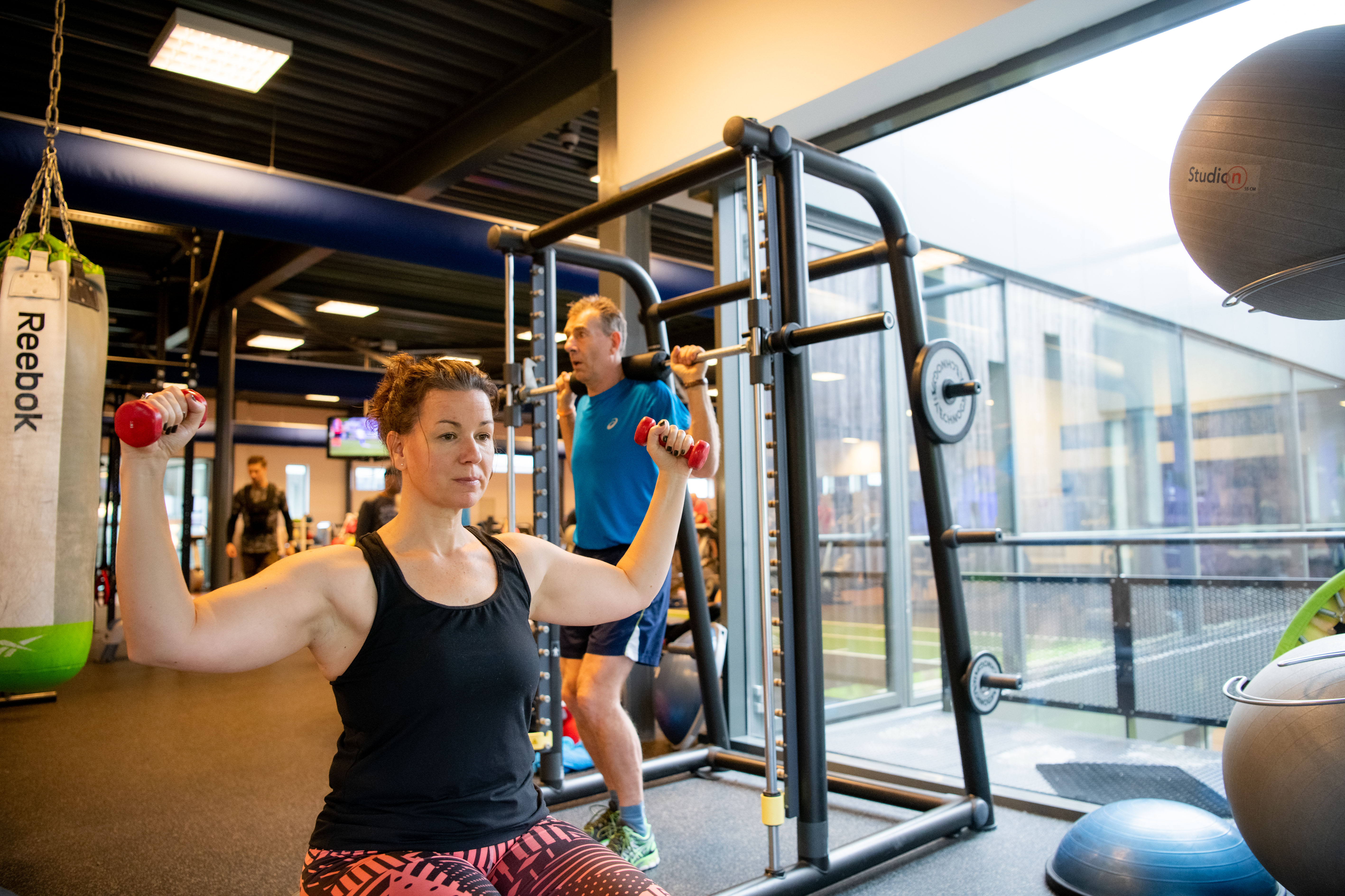 Medisch fitness bij een Optisport locatie. Een vrouw doet onder begeleiding van een instructeur oefeningen om haar doel te bereiken.