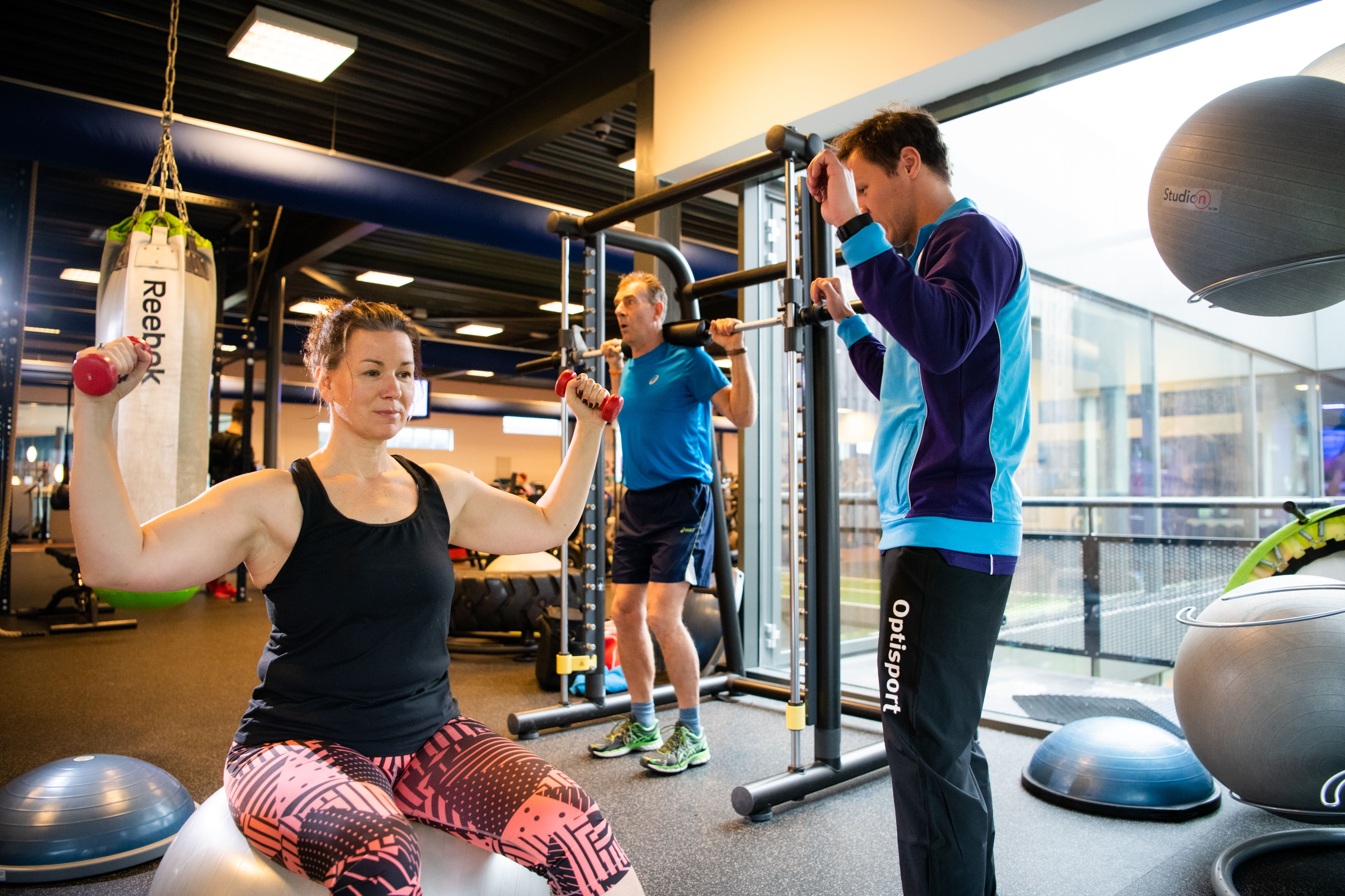 Medisch fitness bij een Optisport locatie. Een vrouw doet onder begeleiding van een instructeur oefeningen om haar doel te bereiken.