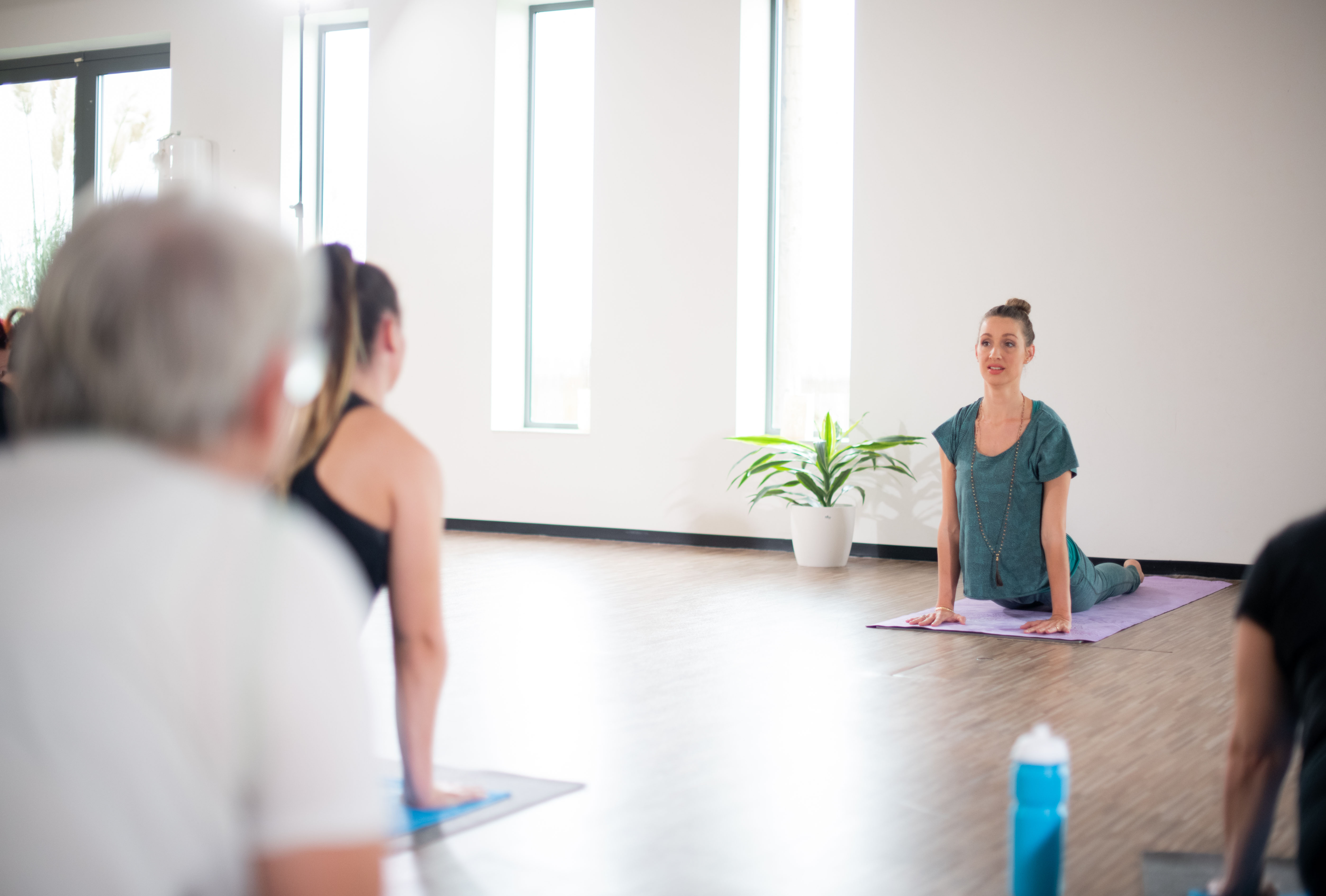 Tijdens de poweryoga zijn mensen oefeningen aan het doen bij een groepsles van Optisport.