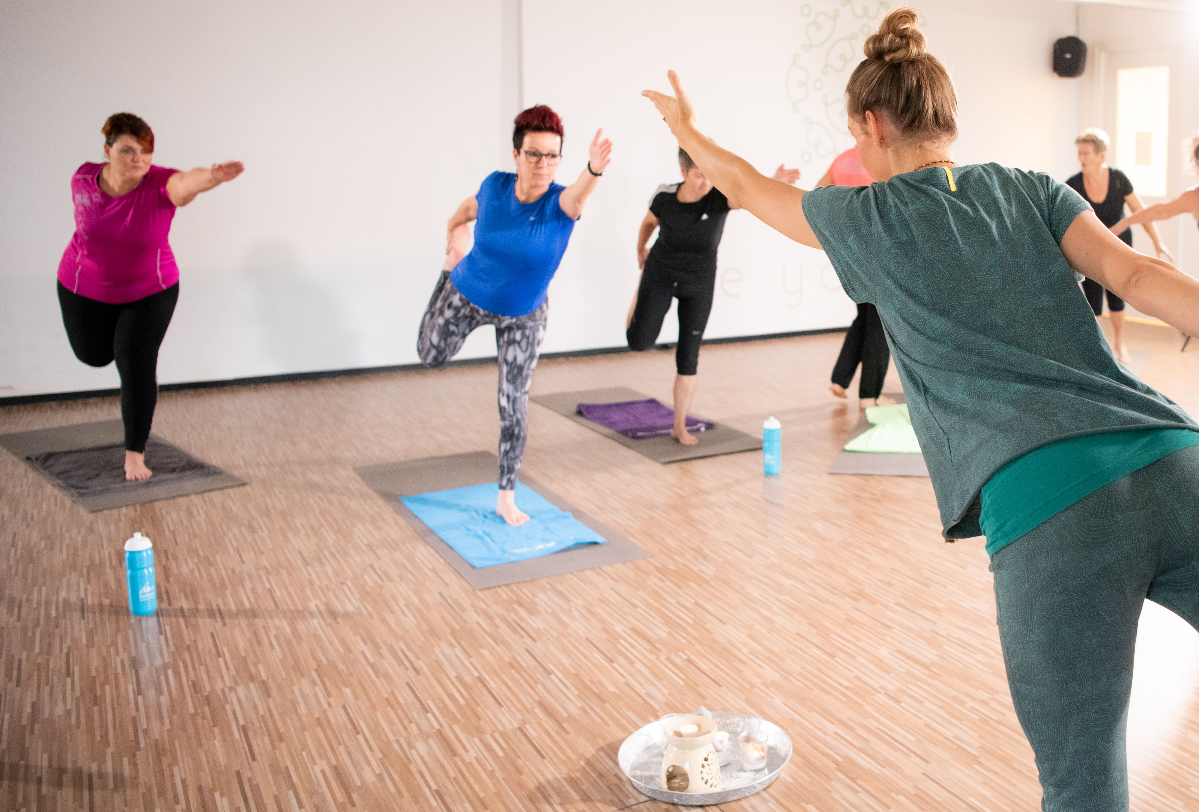 Vinyasa yoga bij Optisport. Vrouwen doen de oefening na van de instructeur tijdens de yogales.