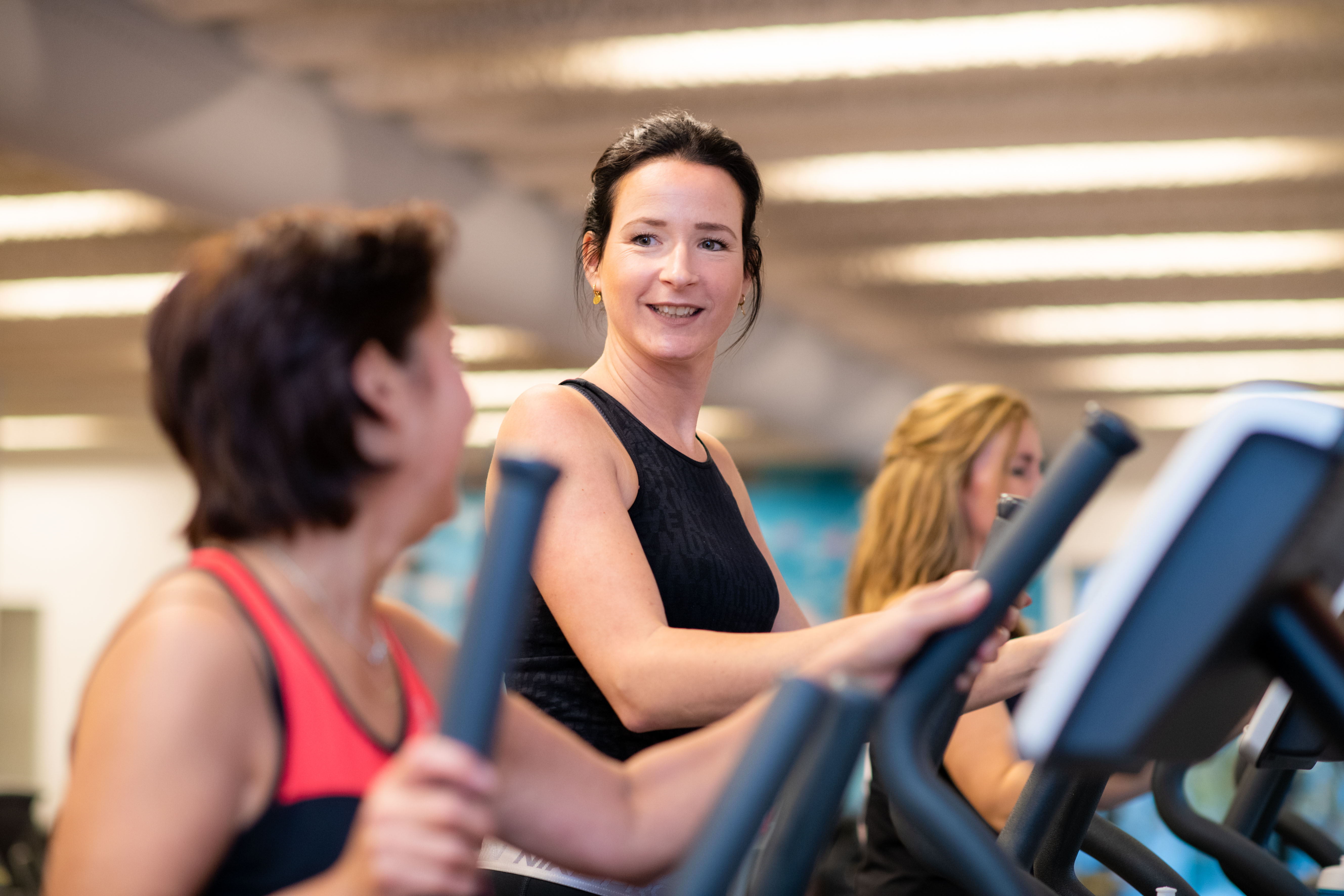 Twee vrouwen hebben plezier op de loopband bij een sportschool van Optisport