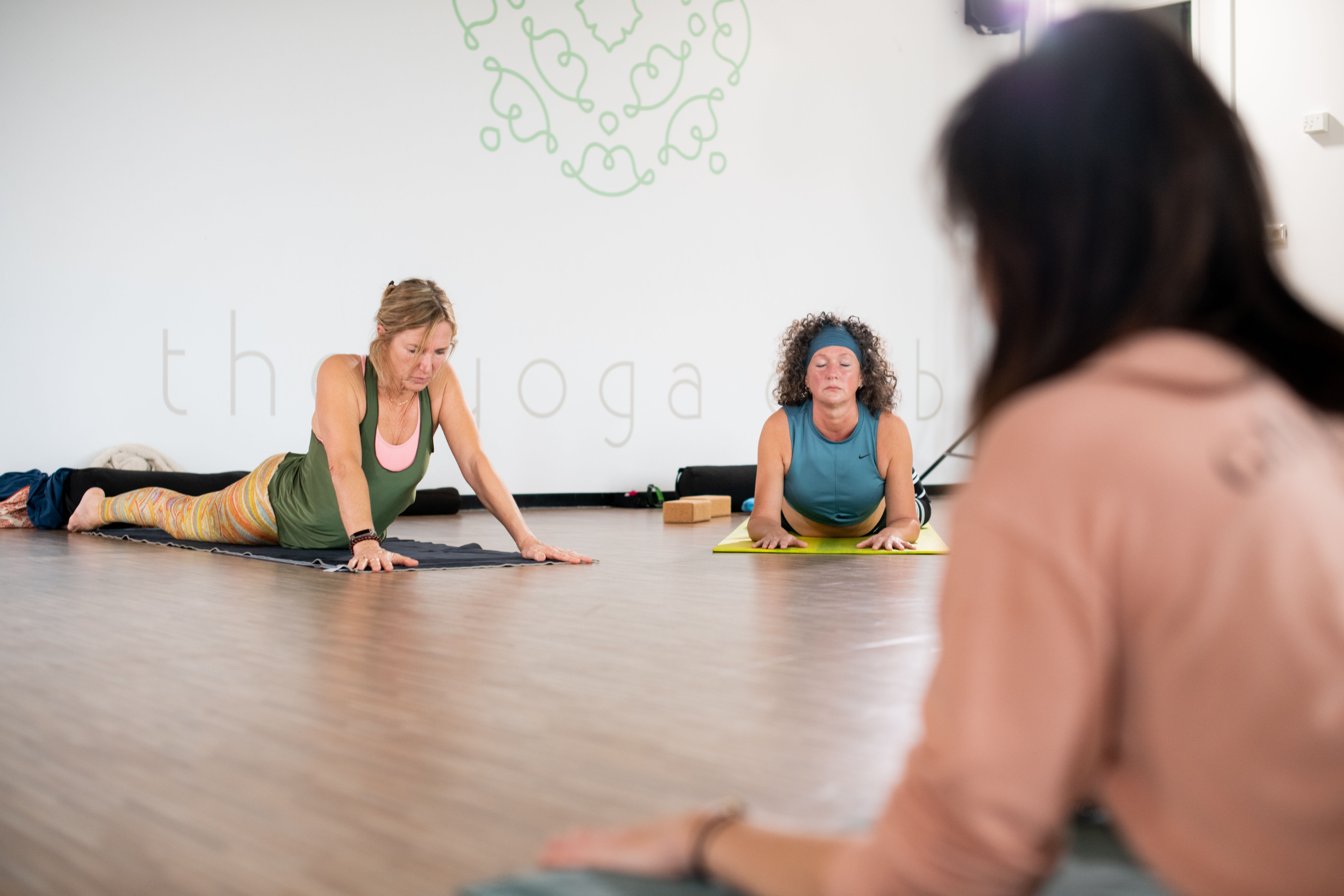 Yin Yoga bij Optisport. Vrouw is oefeningen aan het doen om zo haar gewrichten mobiel te maken onder begeleiding van een instructeur.