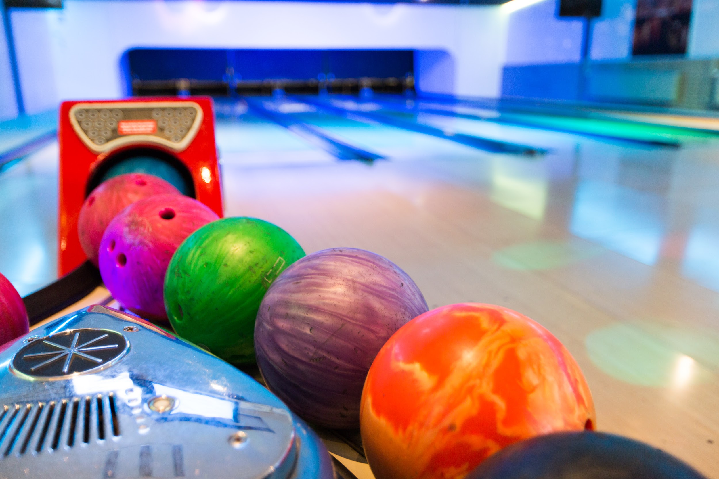 Vier bowlingballen naast elkaar op de bowlingbaan.