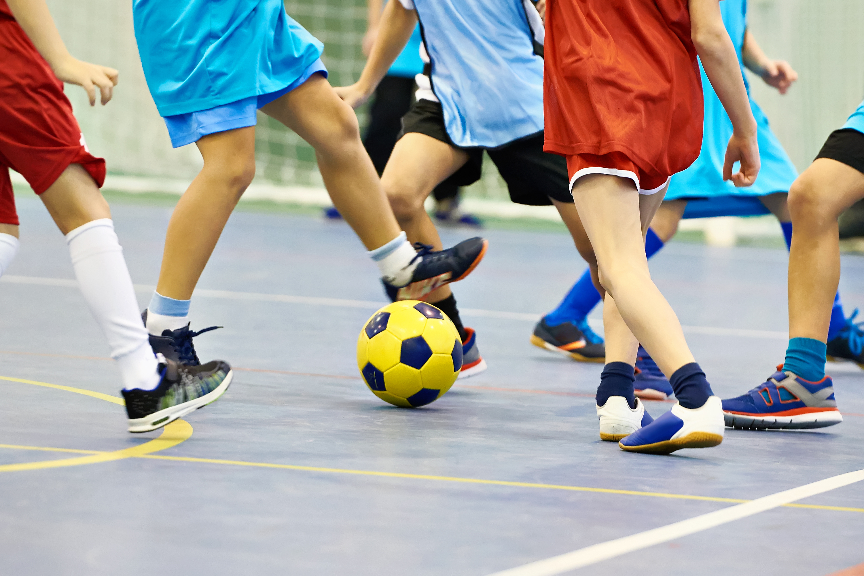 Een groep kinderen is aan het voetballen tijdens een sporthalfeestje.