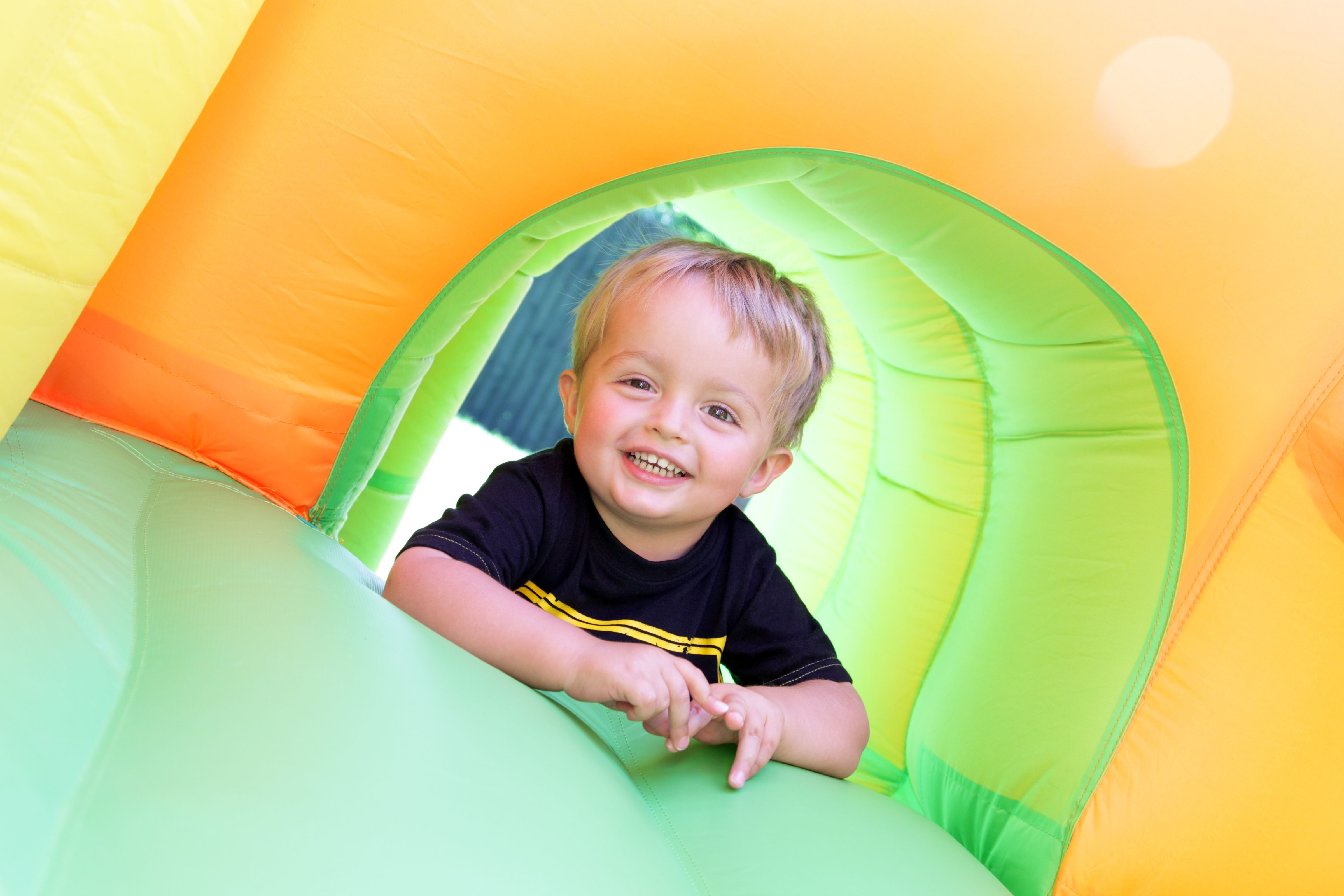 Jongen is aan het lachen tijdens een kinderfeestje op een springkussen. Hij is aan het lachen en maakt plezier.