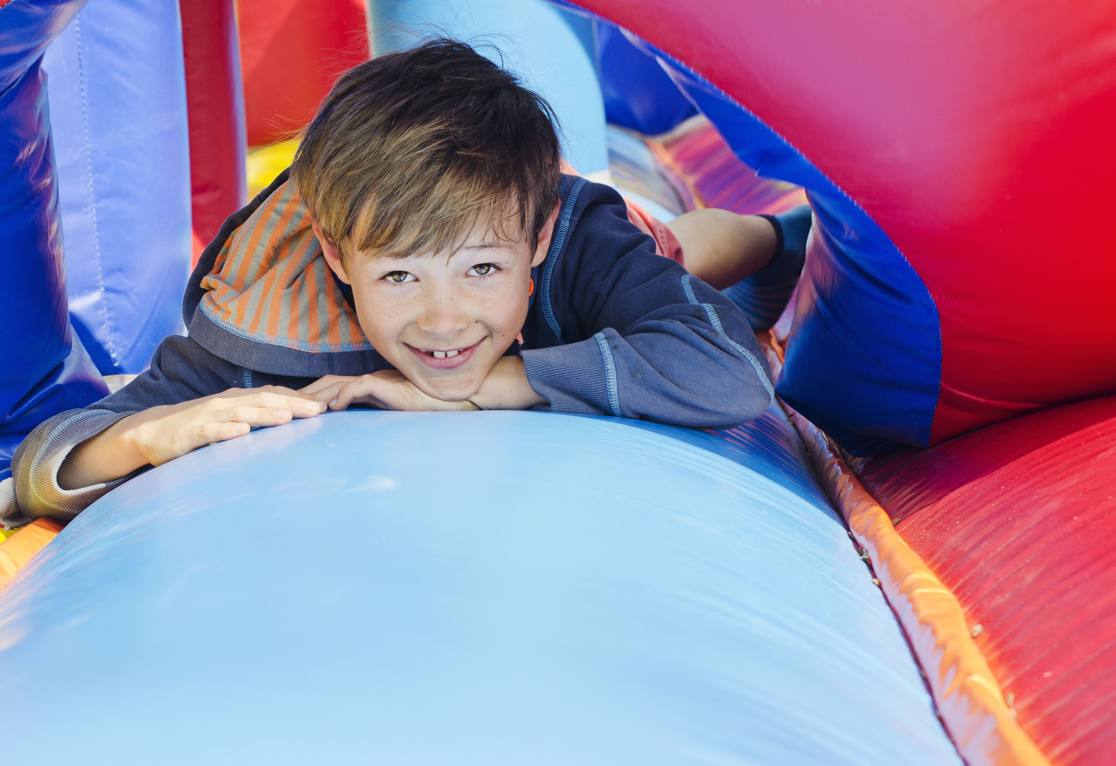 Jongen is aan het lachen tijdens een kinderfeestje op een springkussen. Hij is aan het lachen en maakt plezier.