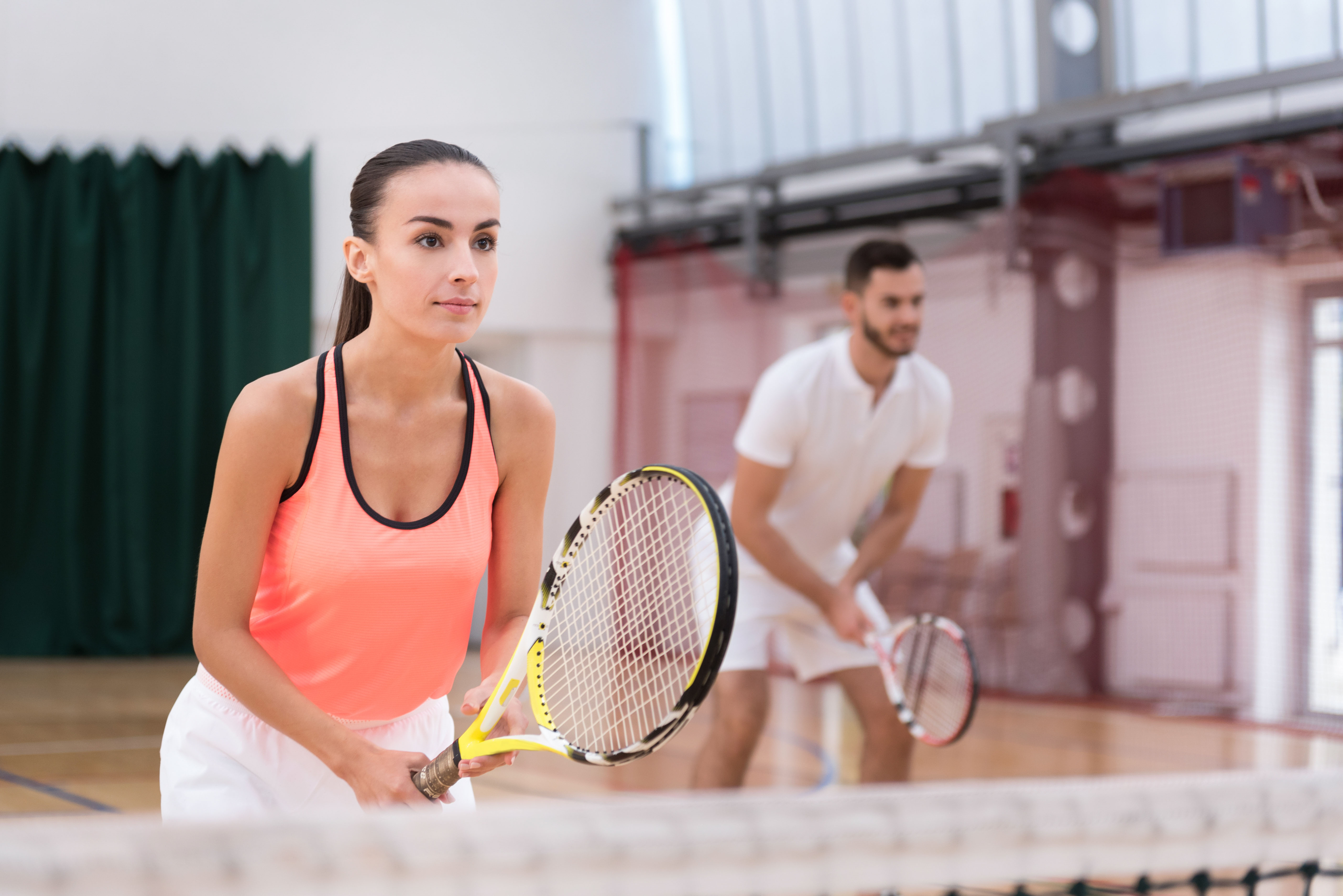 Man en een vrouw zijn een tenniswedstrijd aan het spelen op een tennisbaan.