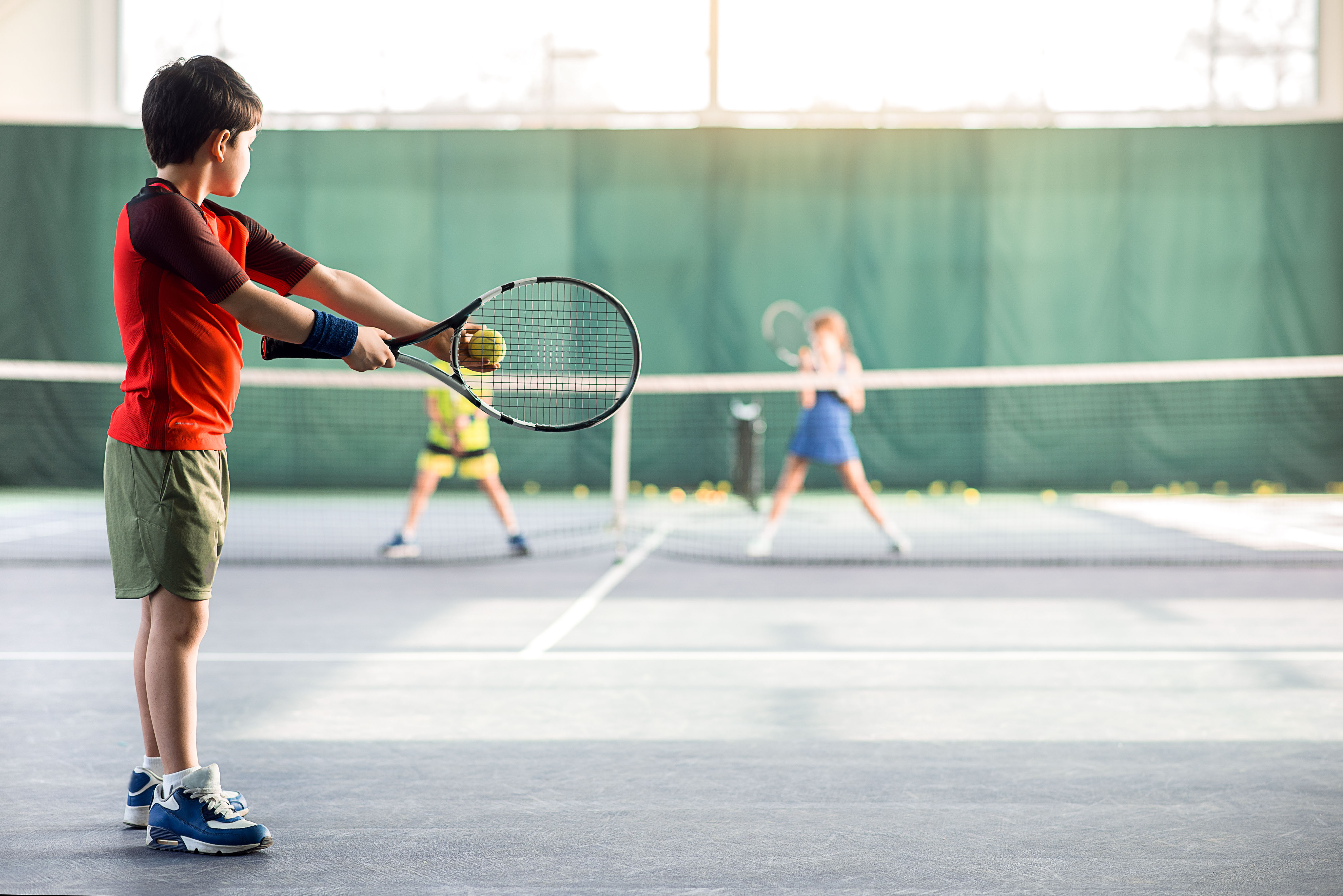 Een jongen is aan het leren tijdens een tennistraining.