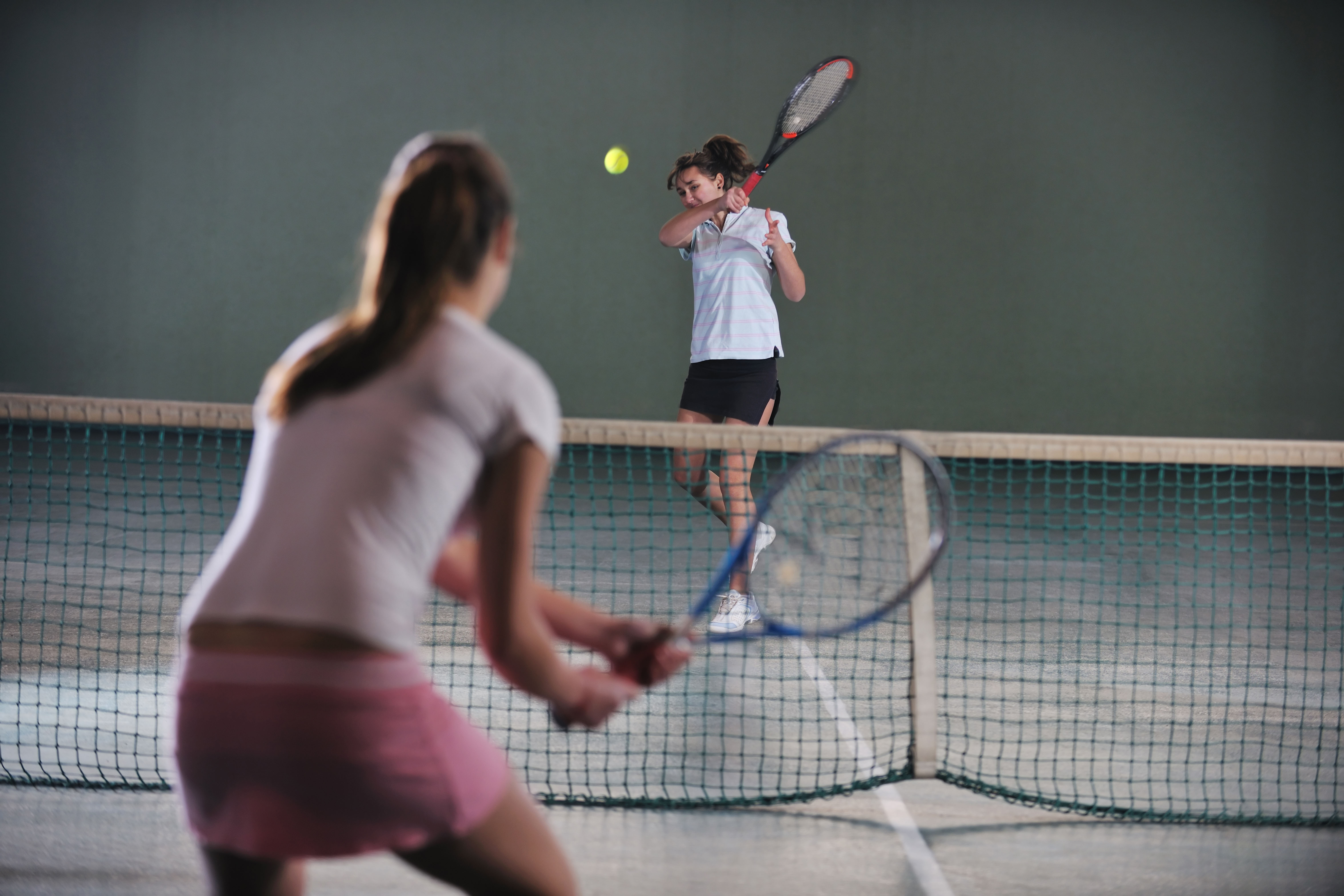 Twee mensen zijn een bal aan het overslaan op de tennisbaan.