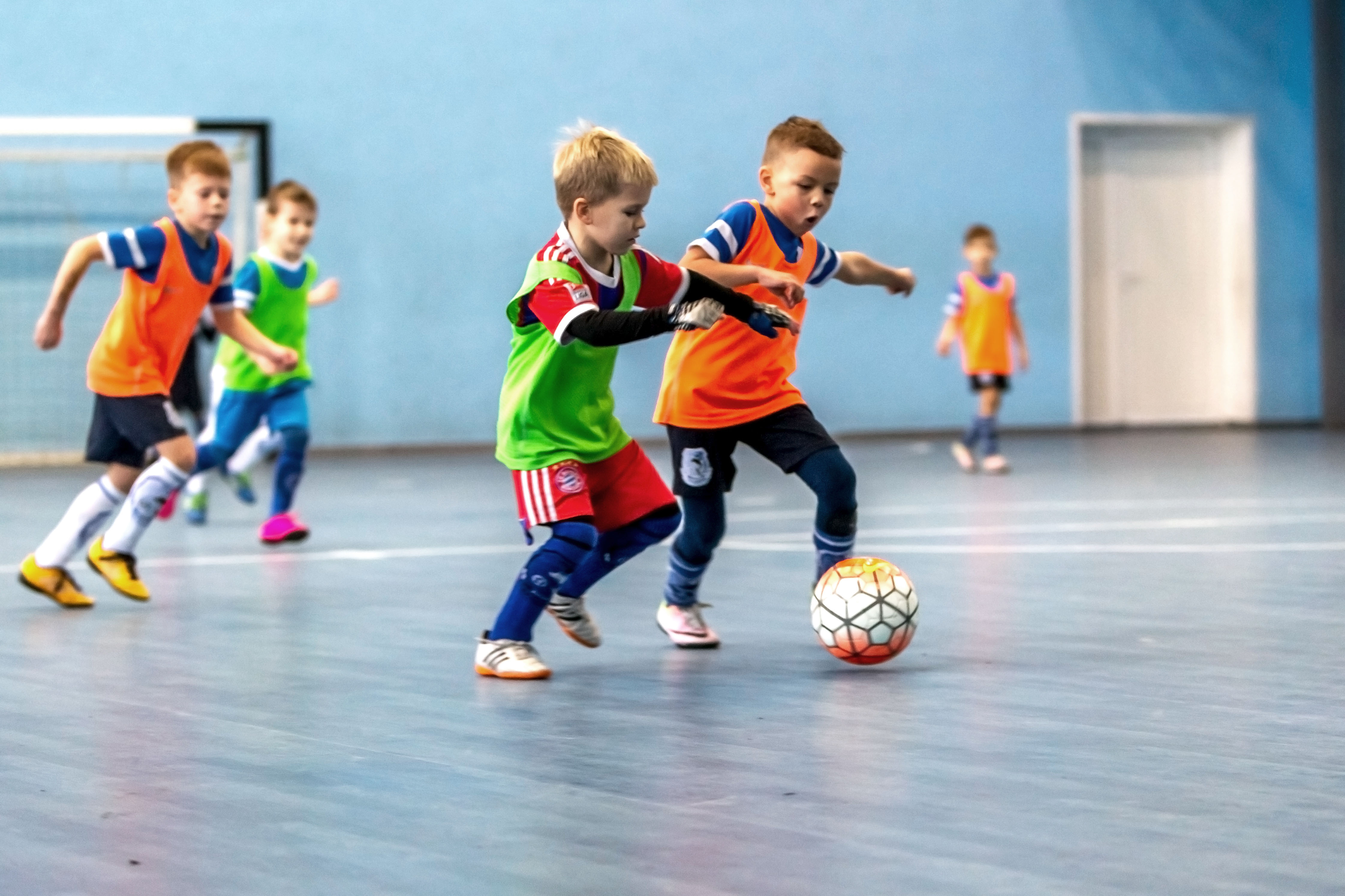 Kinderen zijn aan het voetballen tijdens een zaalvoetbalfeestje.