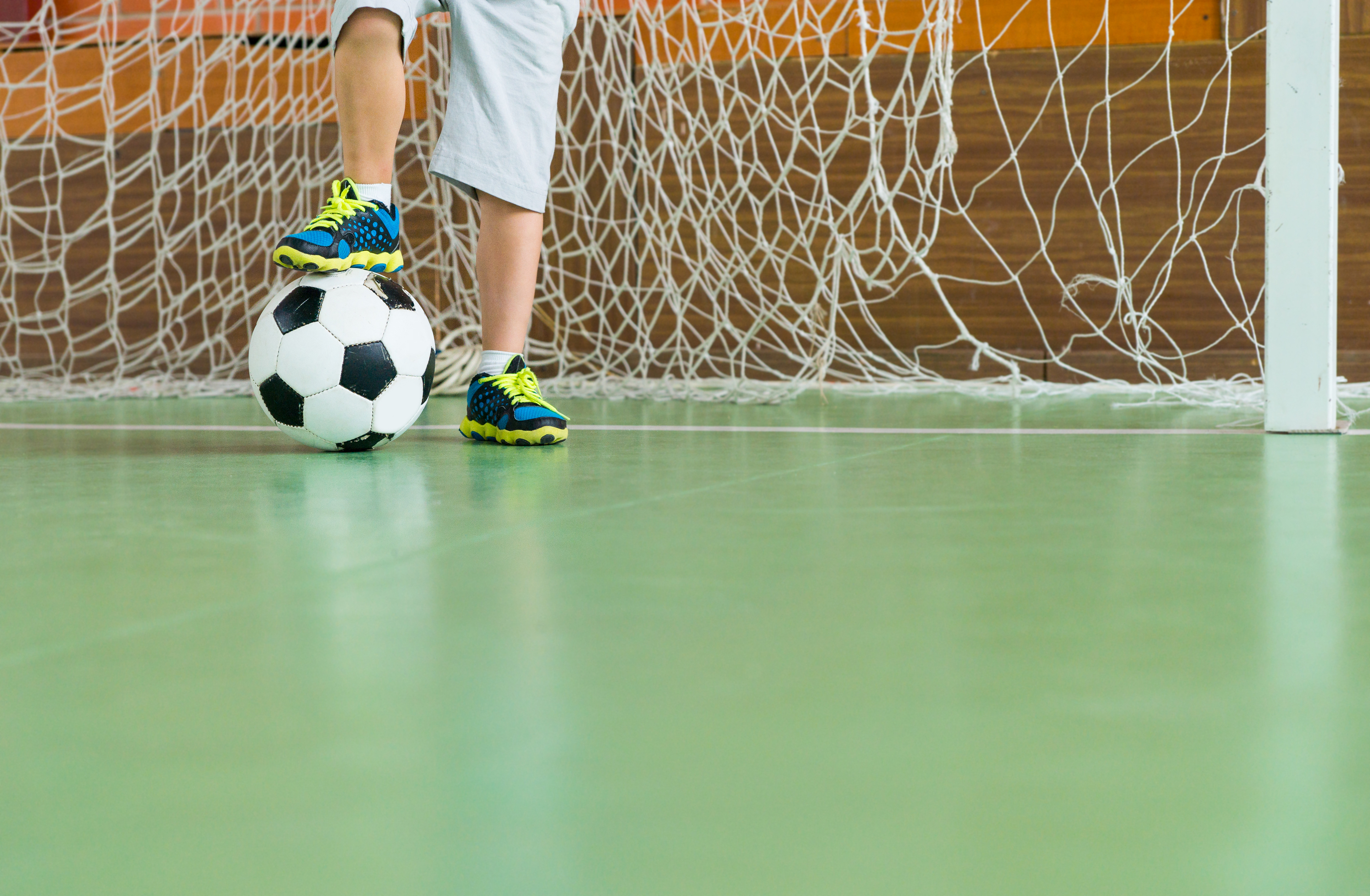 Een jongen houdt de voetbal onder zijn schoen.