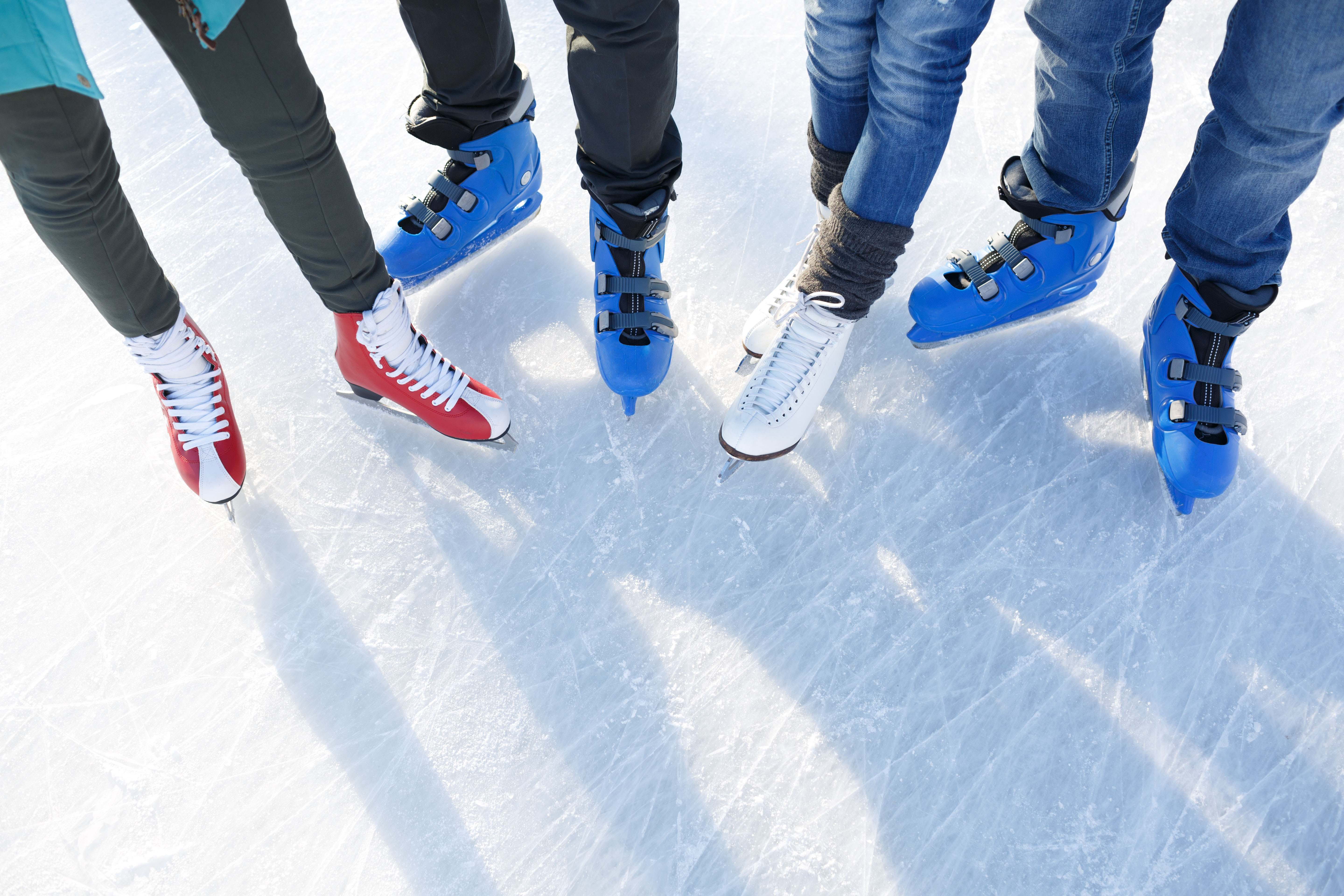 Benen en schaatsen van vier personen op het ijs