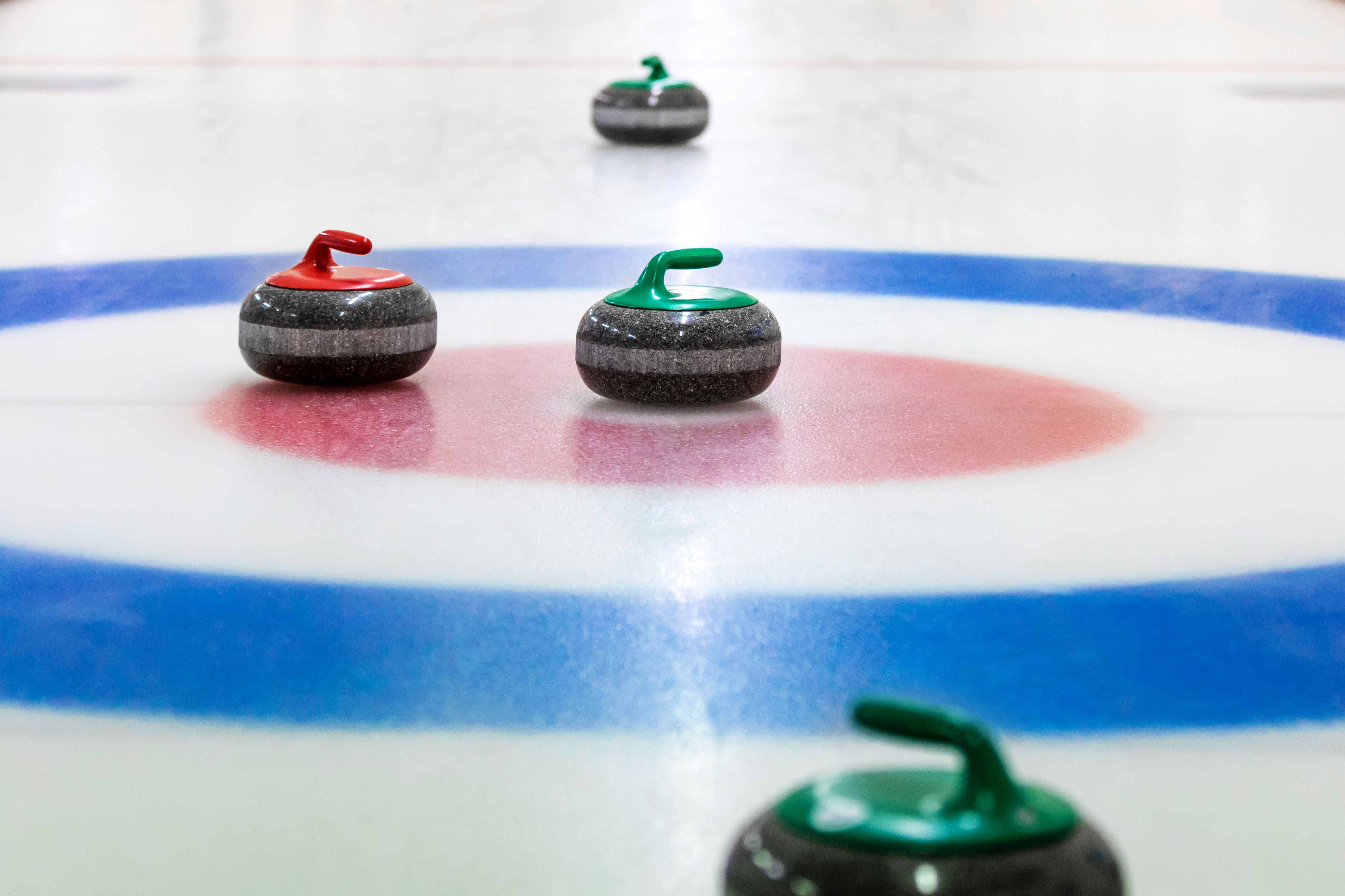Groepsactiviteit op het ijs bij een Optisport locatie. Verschillende activiteiten, zoals curling.