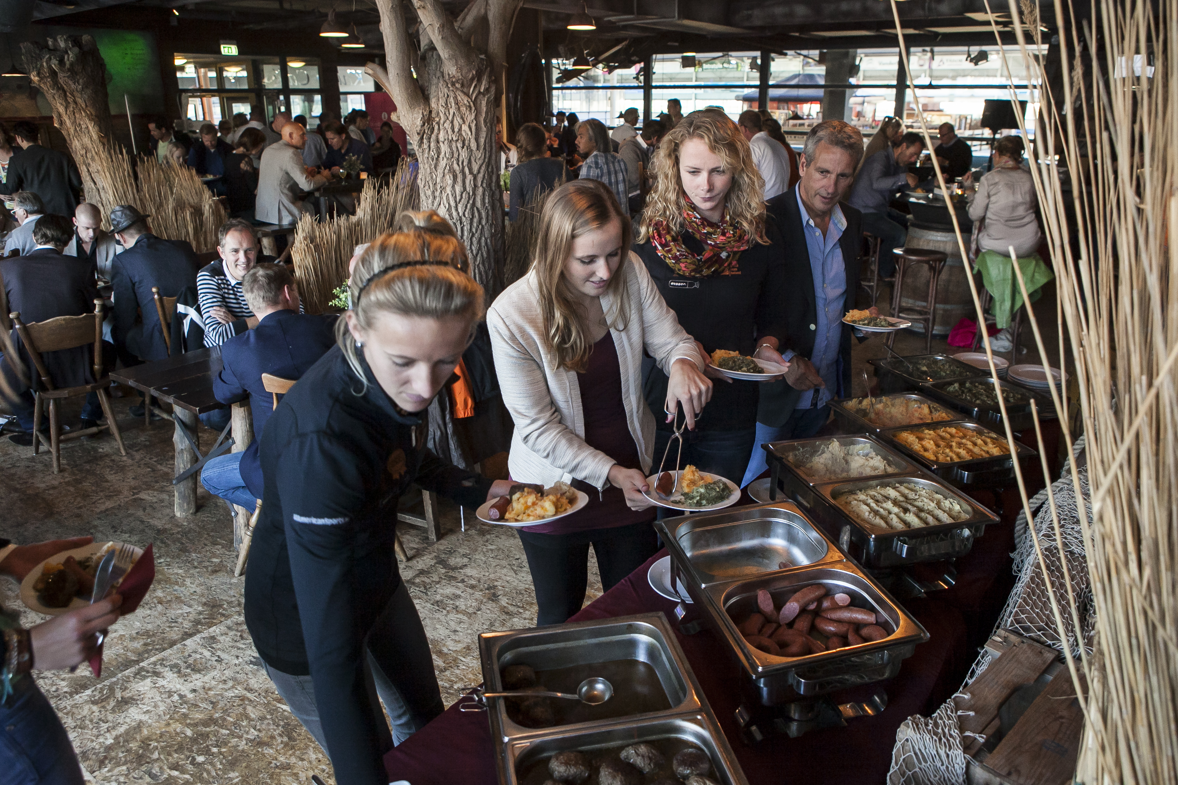 Lopend buffet waar lekker wordt opgeschept door 3 vrouwen en een man