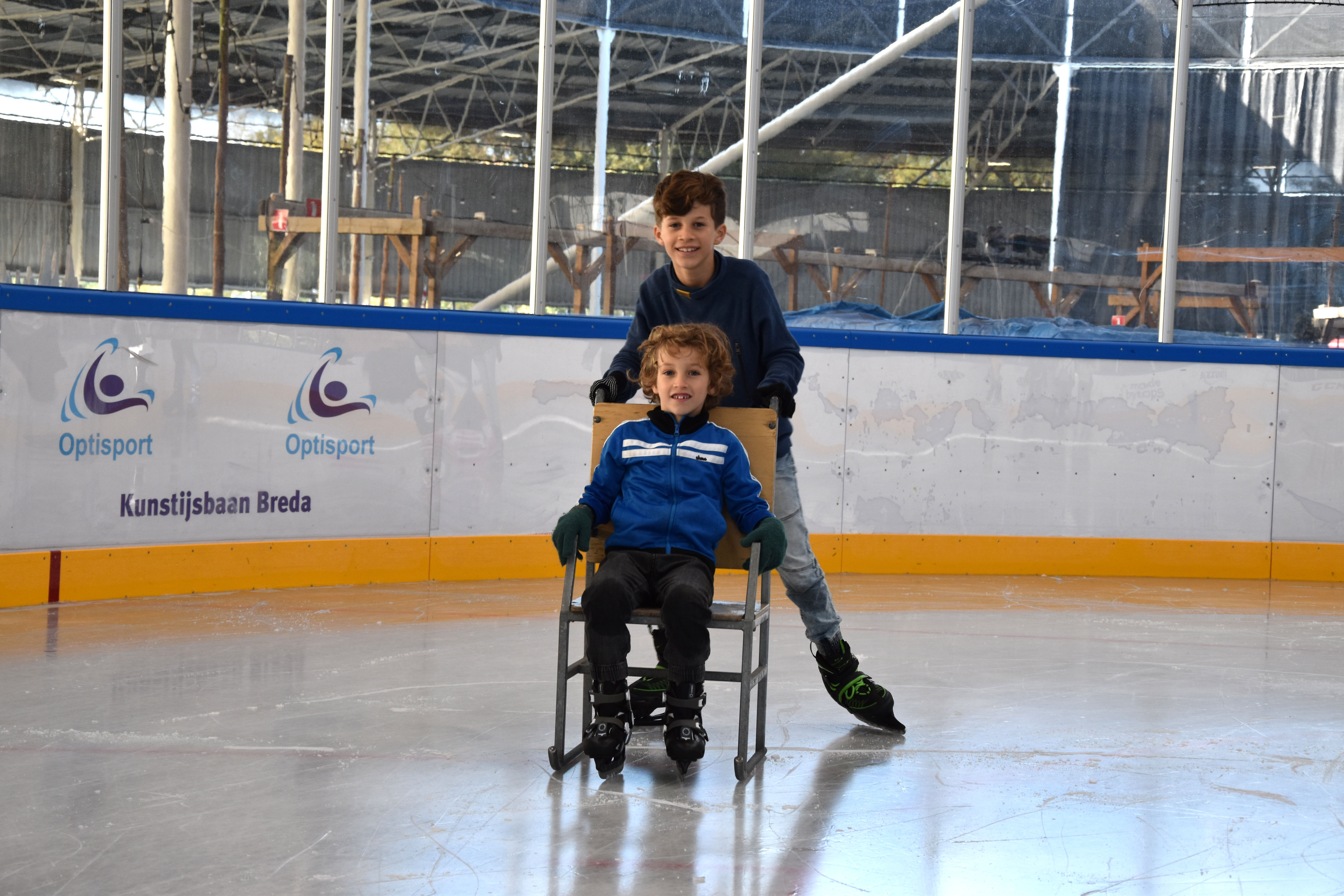 Kinderen zijn aan het schoolschaatsen en maken gebruik van een stoel op het ijs.