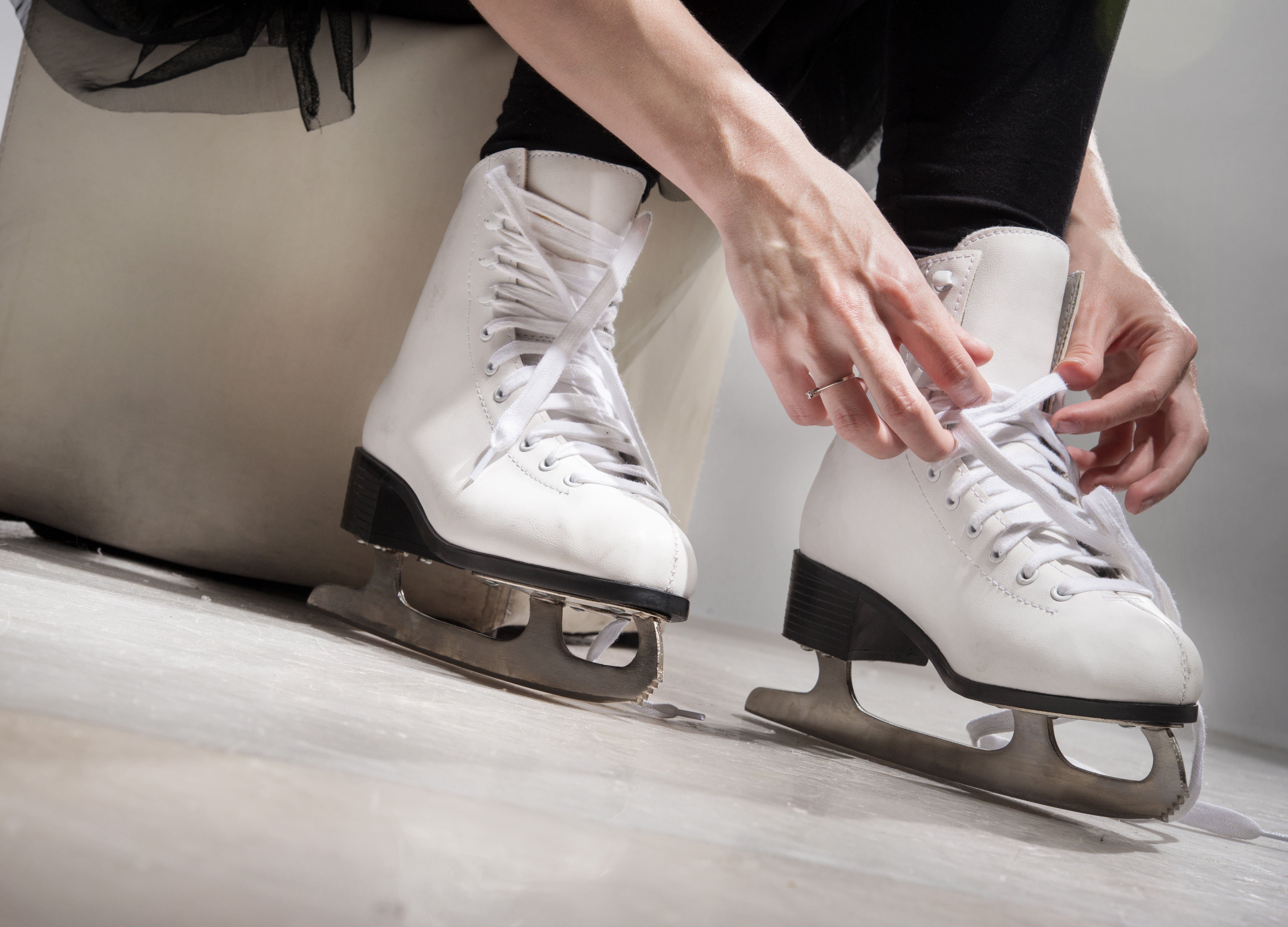 Persoon trekt zijn schaatsen aan om te gaan schaatsen op een ijsbaan.