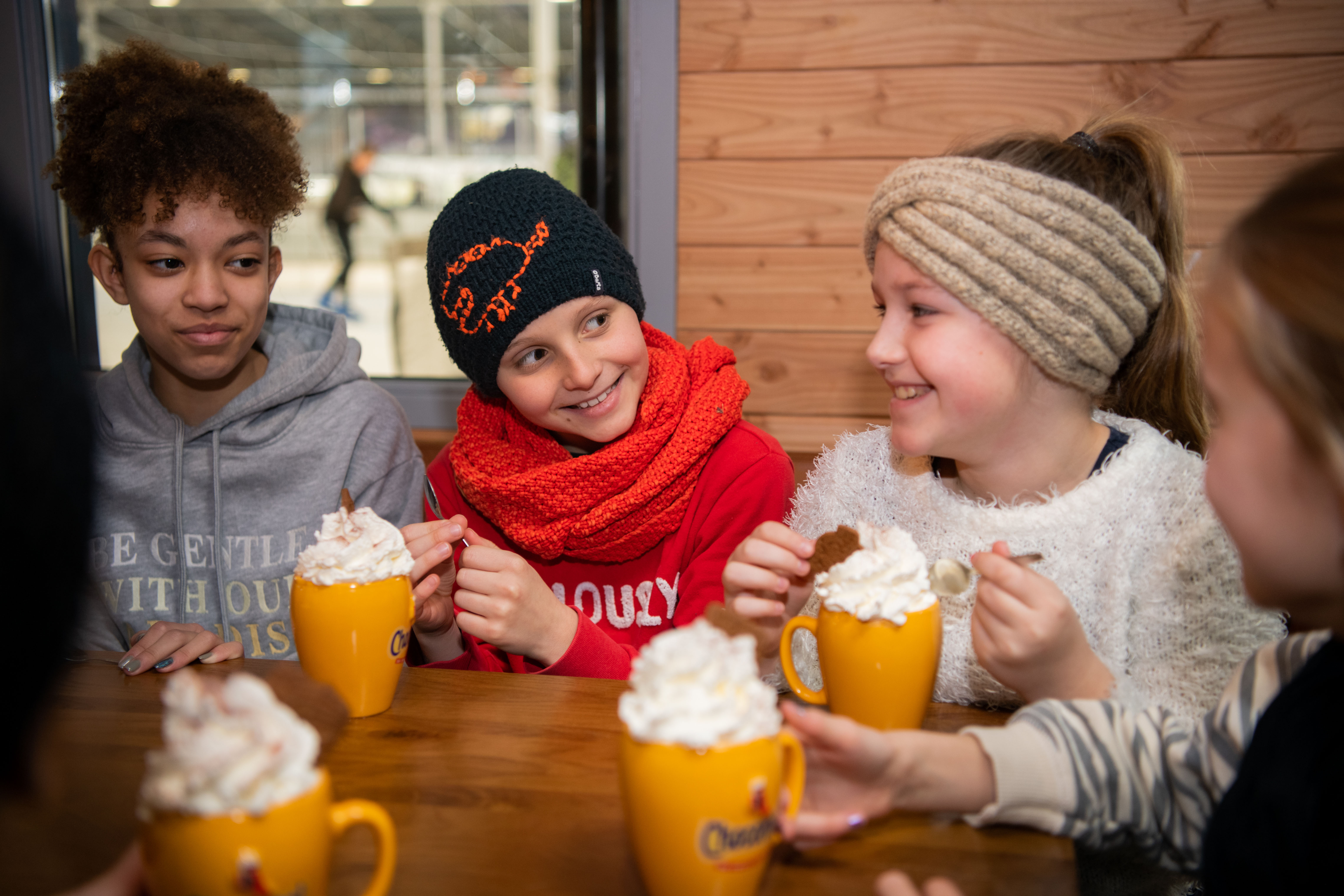 Kinderen zitten na het schaatsen in de Horeca te genieten van drinken en eten.