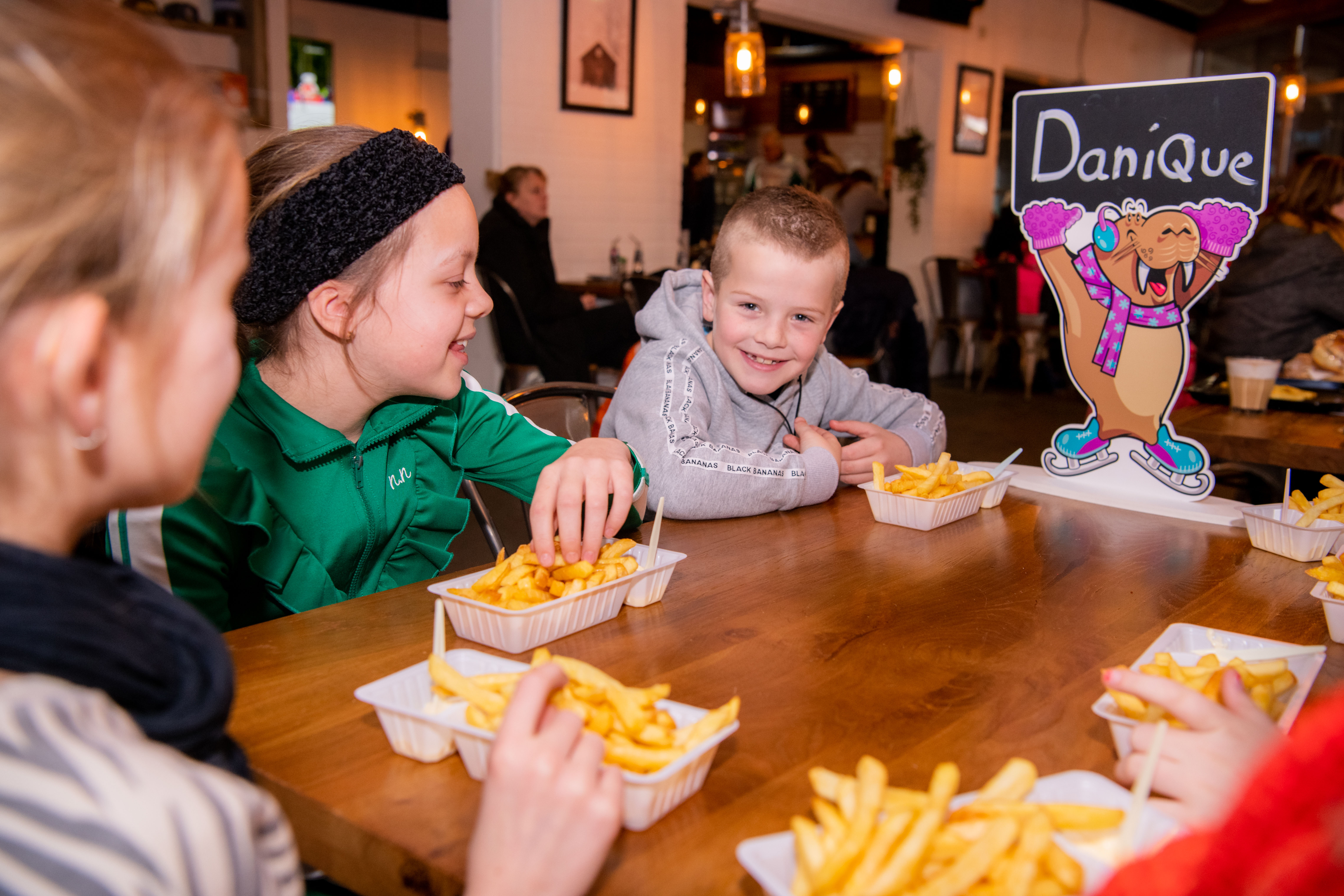 Schaatsfeestje bij een Optisport locatie. Kinderen hebben plezier op en naast het ijs tijdens het feestje met eten en drinken..