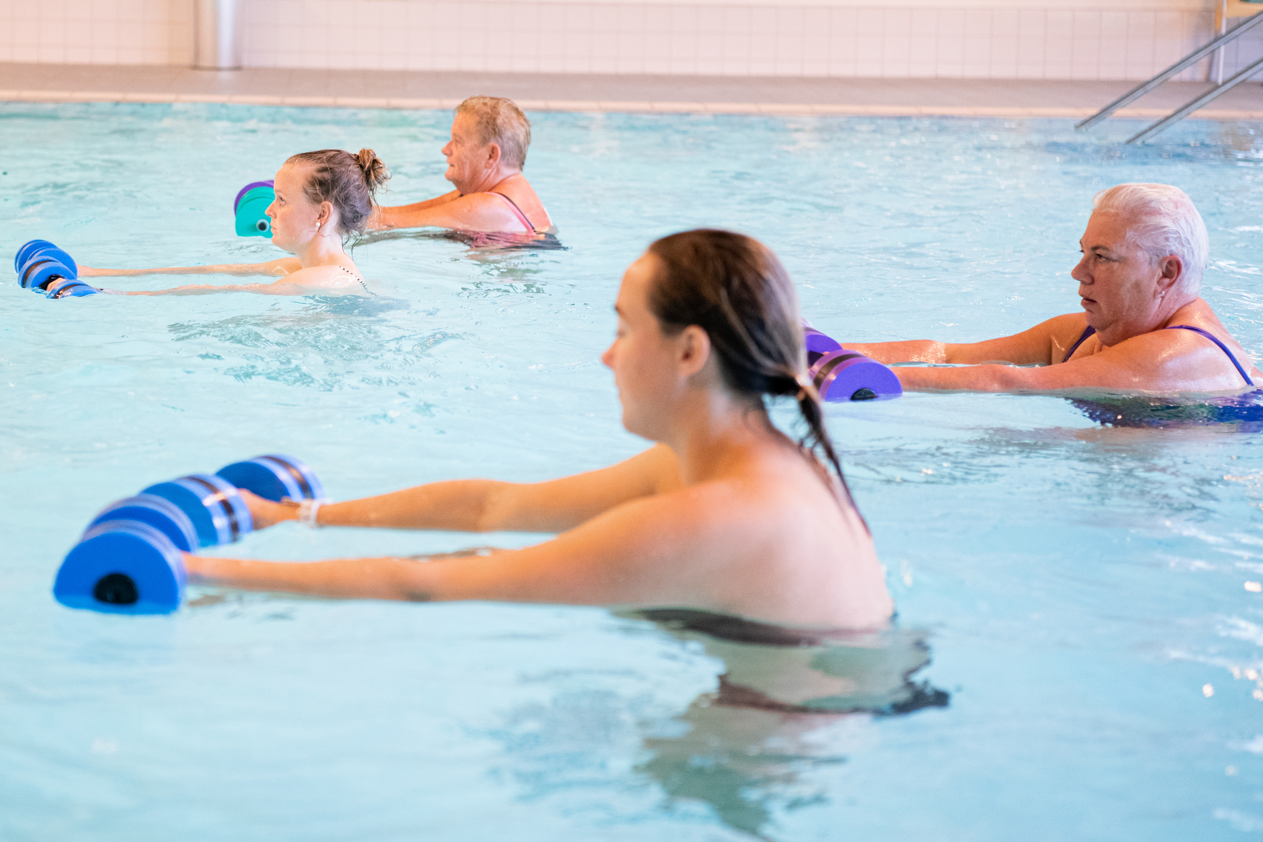 Vier mensen doen oefeningen met gewichten in het water