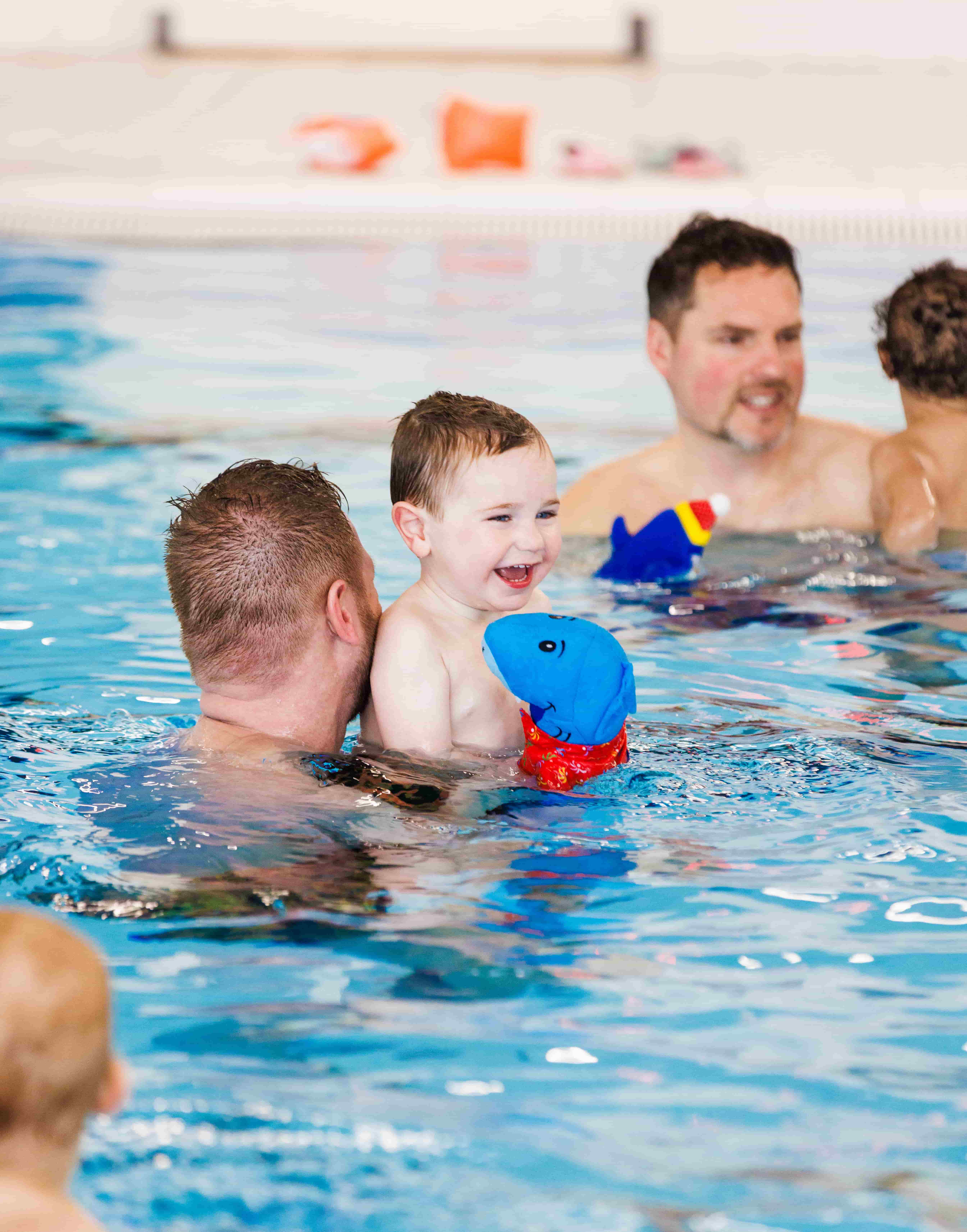 Tijdens de peuterzwemles van Liz & Wes hebben een vader en zijn zoontje dikke pret in het zwembad van Optisport.  