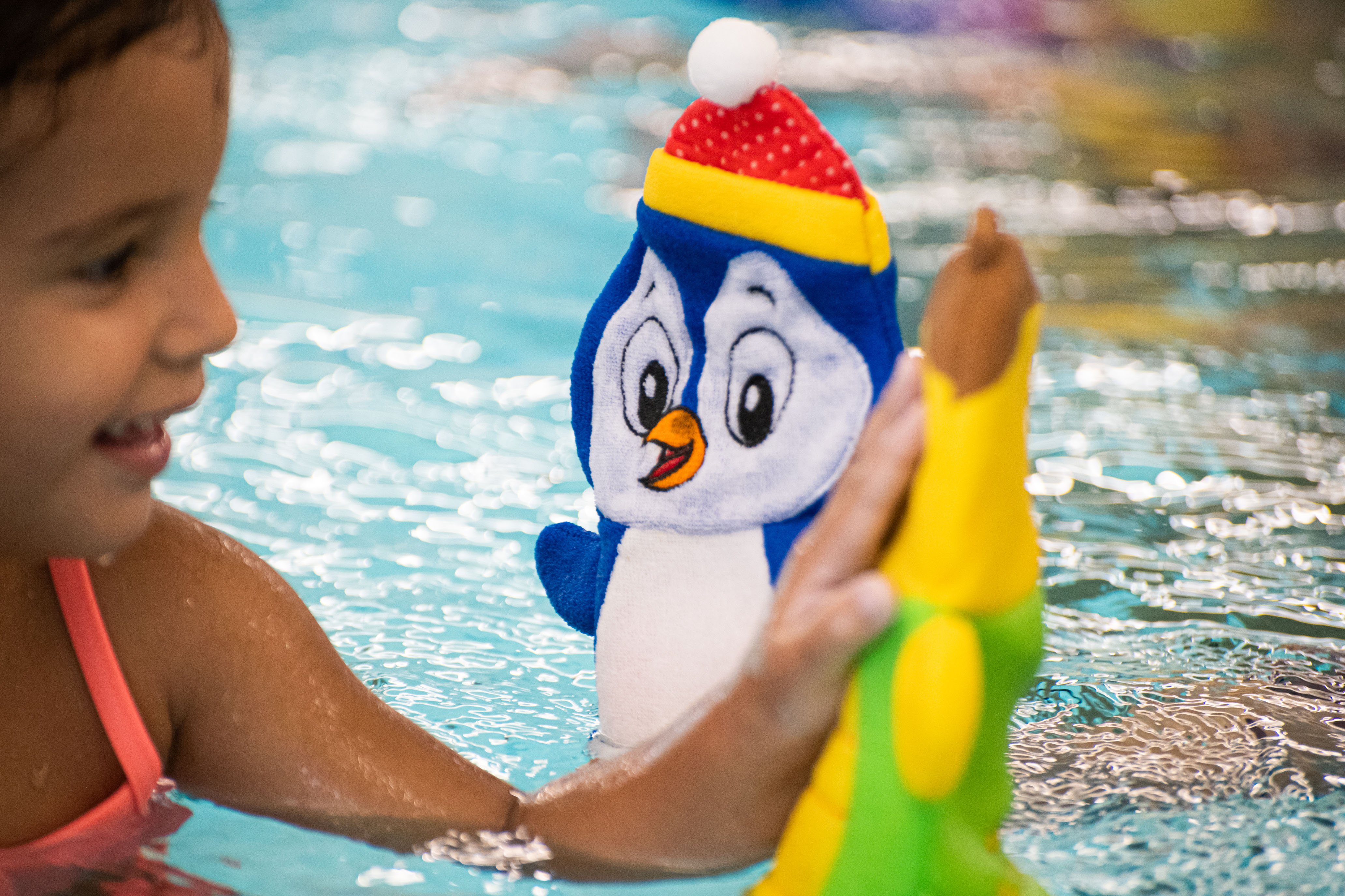 Een kind is vrolijk in het water bezig terwijl de instructeur van Optisport hierbij is.