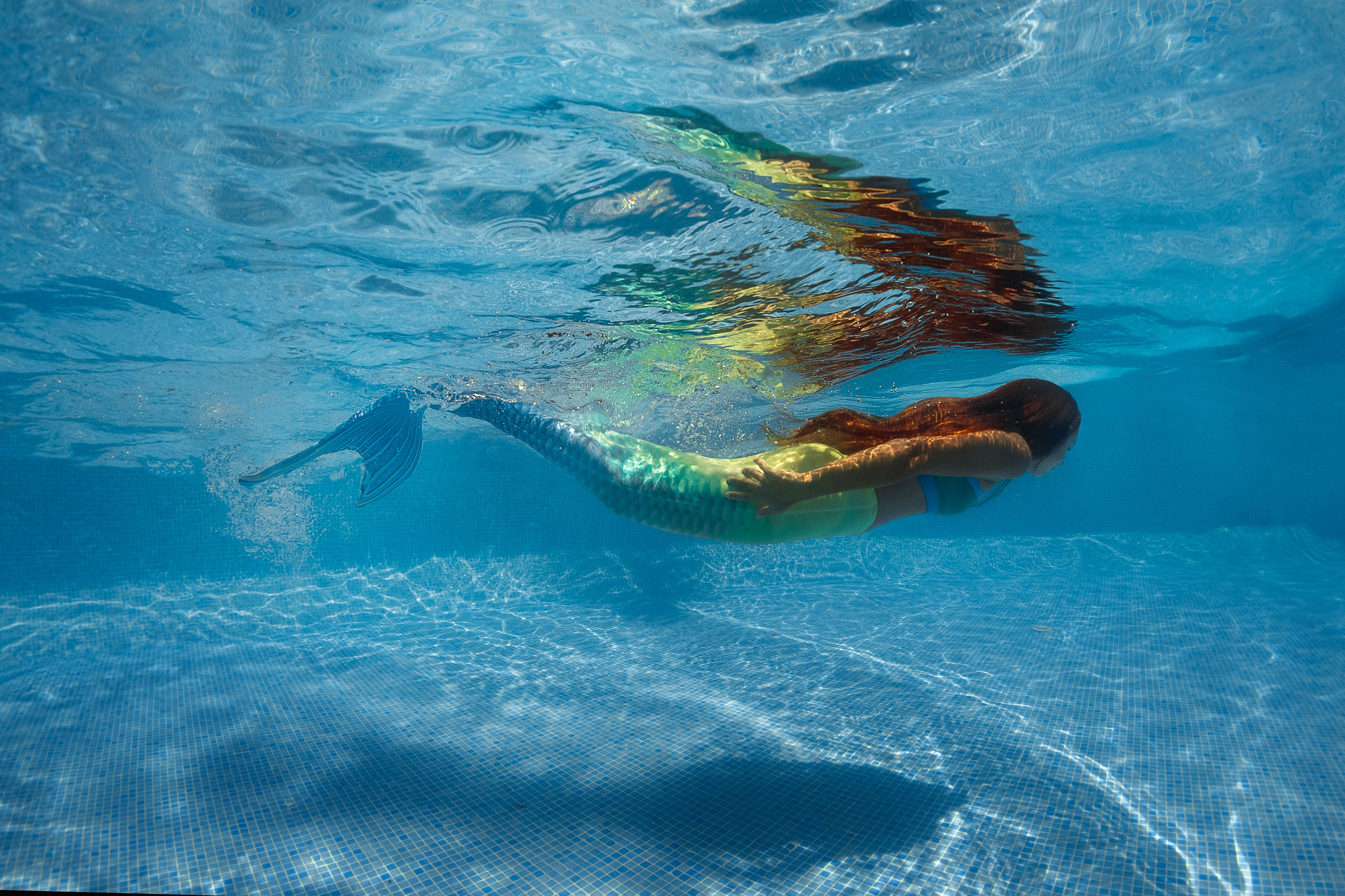 Een meisje is onderwater aan het zwemmen als een zeemeermin in een zwembad van Optisport.