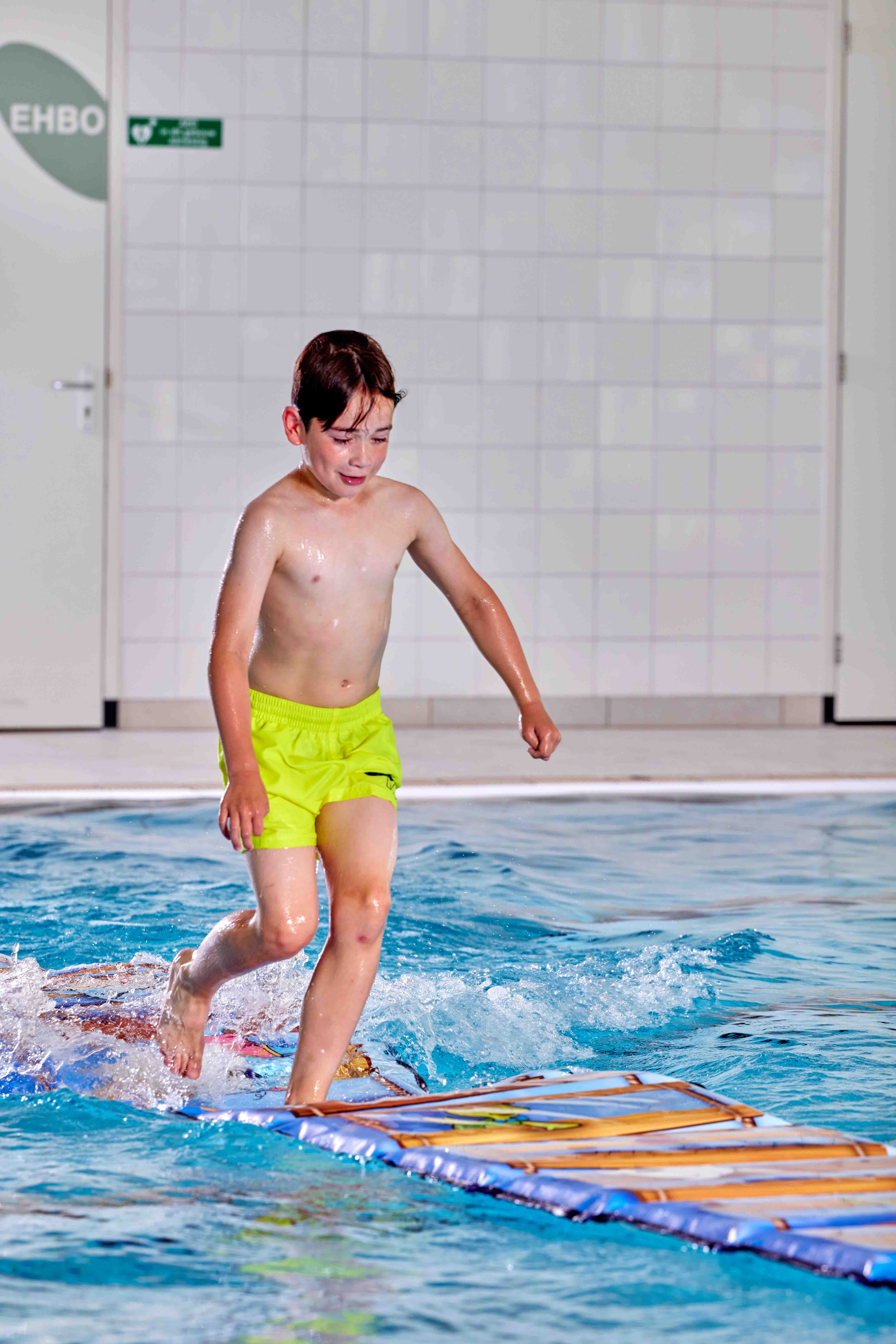 Tijdens Vrijzwemmen in het zwembad van Optisport rent een jongetje behendig over een lange mat die over het water heen is gelegd… zou hij de overkant halen zonder te vallen?