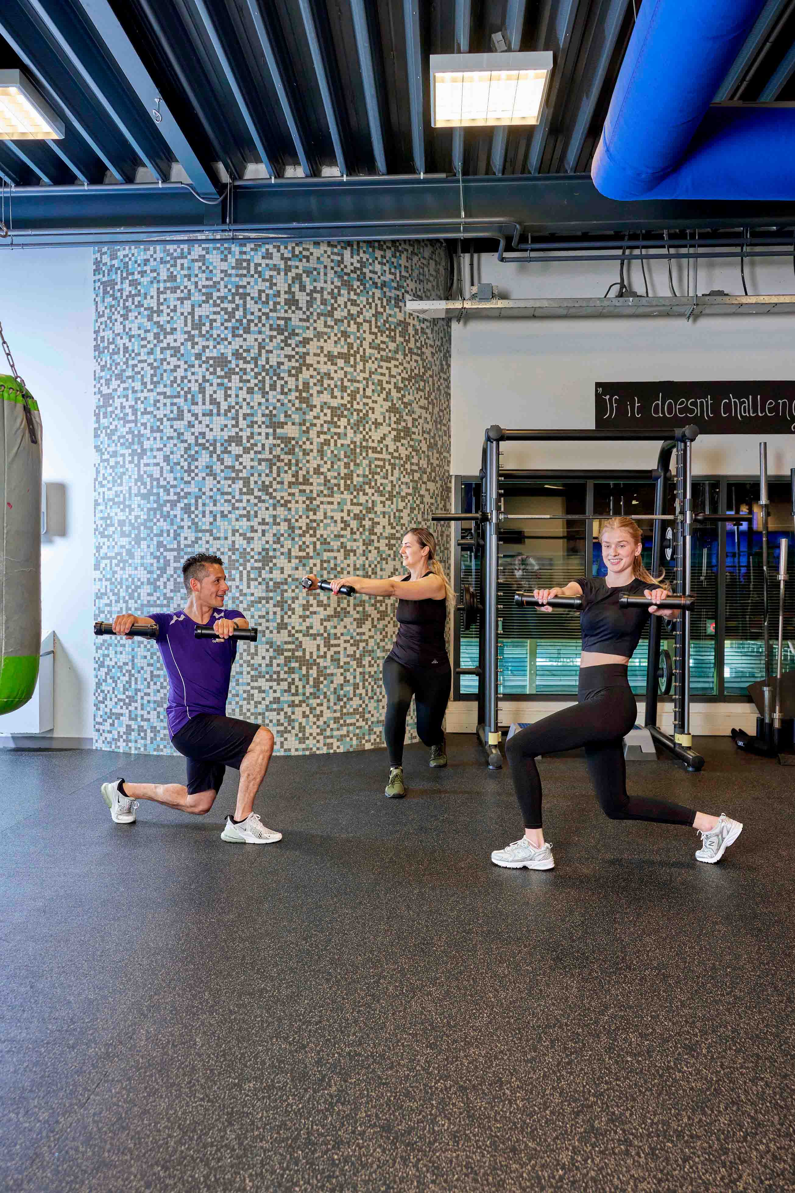 Twee meiden doen onder leiding van een instructeur van Optisport oefeningen met gewichten tijdens de intensieve workout BRN (Body you Really Need). 