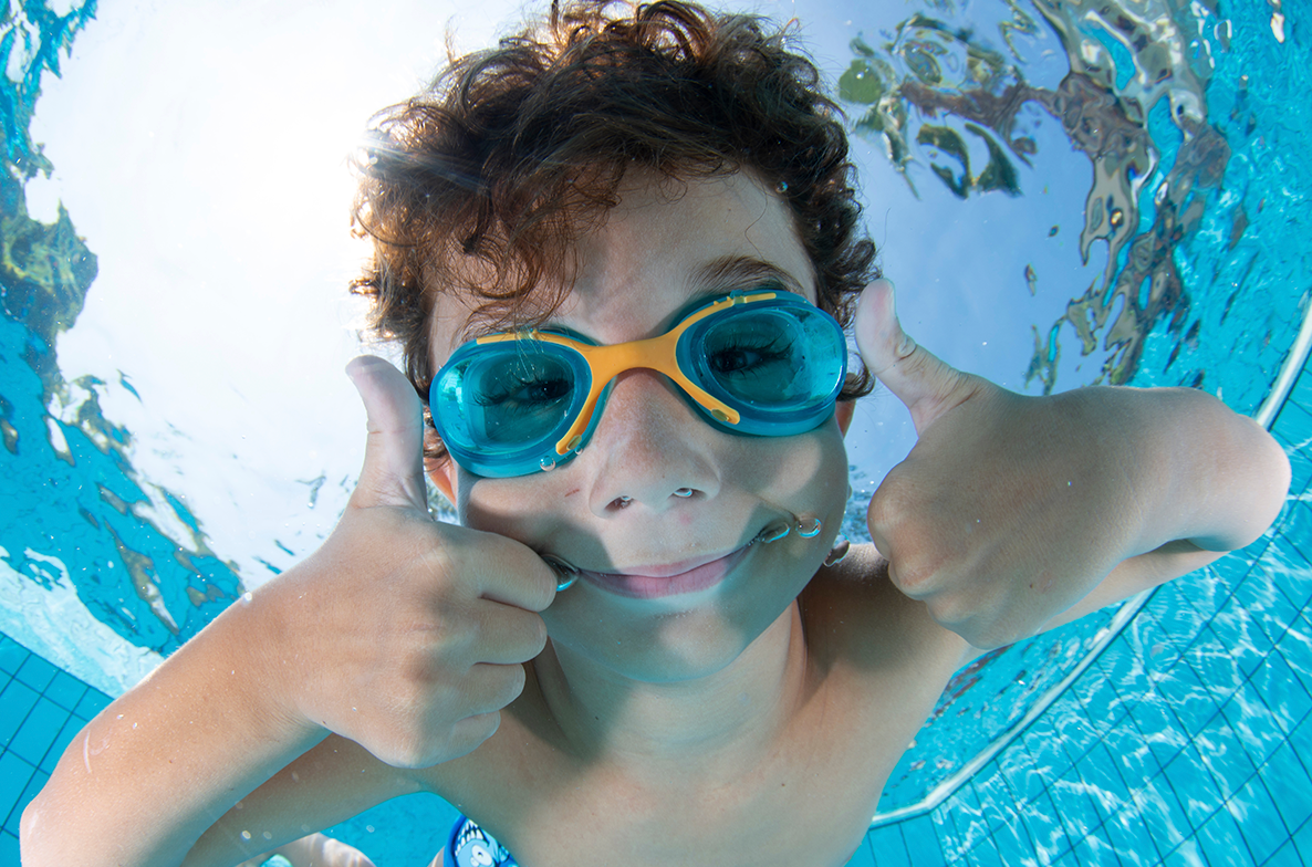 Jongen onderwater met duikbril op twee duimen omhoog