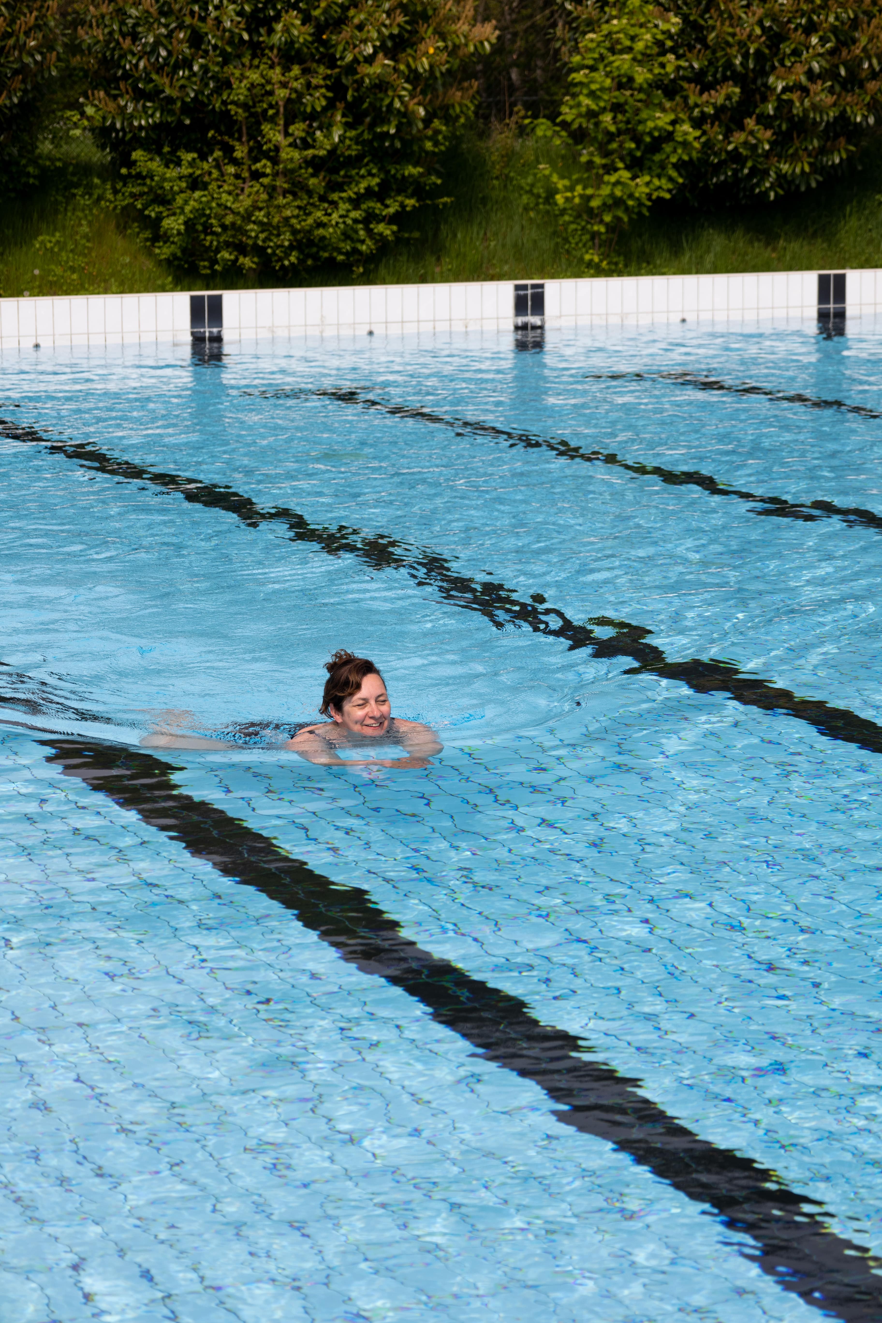 Een dame zwemt heerlijk baantjes in het buitenbad van Optisport, dit kan zowel in de ochtend als in de avonduren.