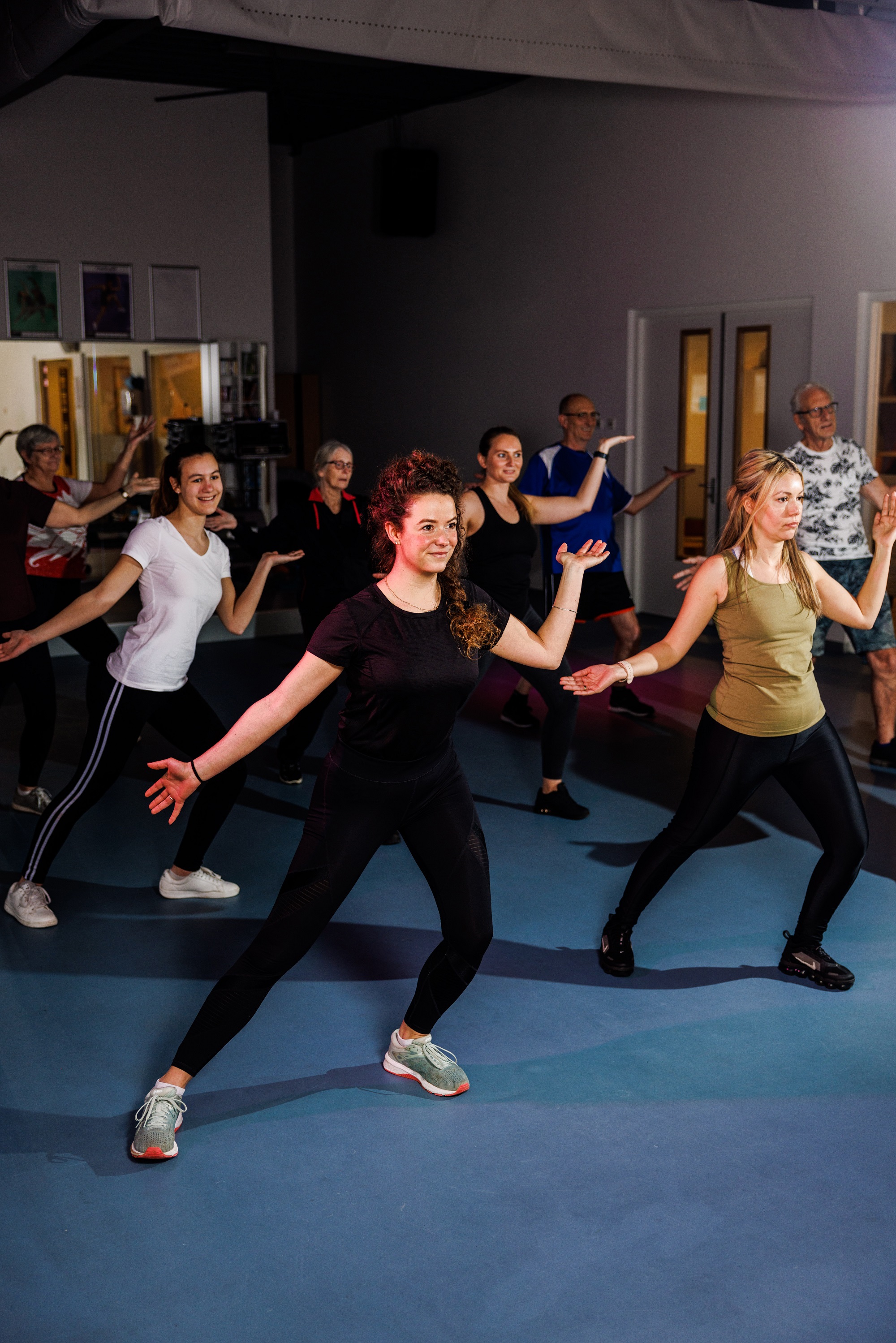 Een groep sporters staat te dansen tijdens een groepsles Club Dance Party bij een van de healthclubs van Optisport. 