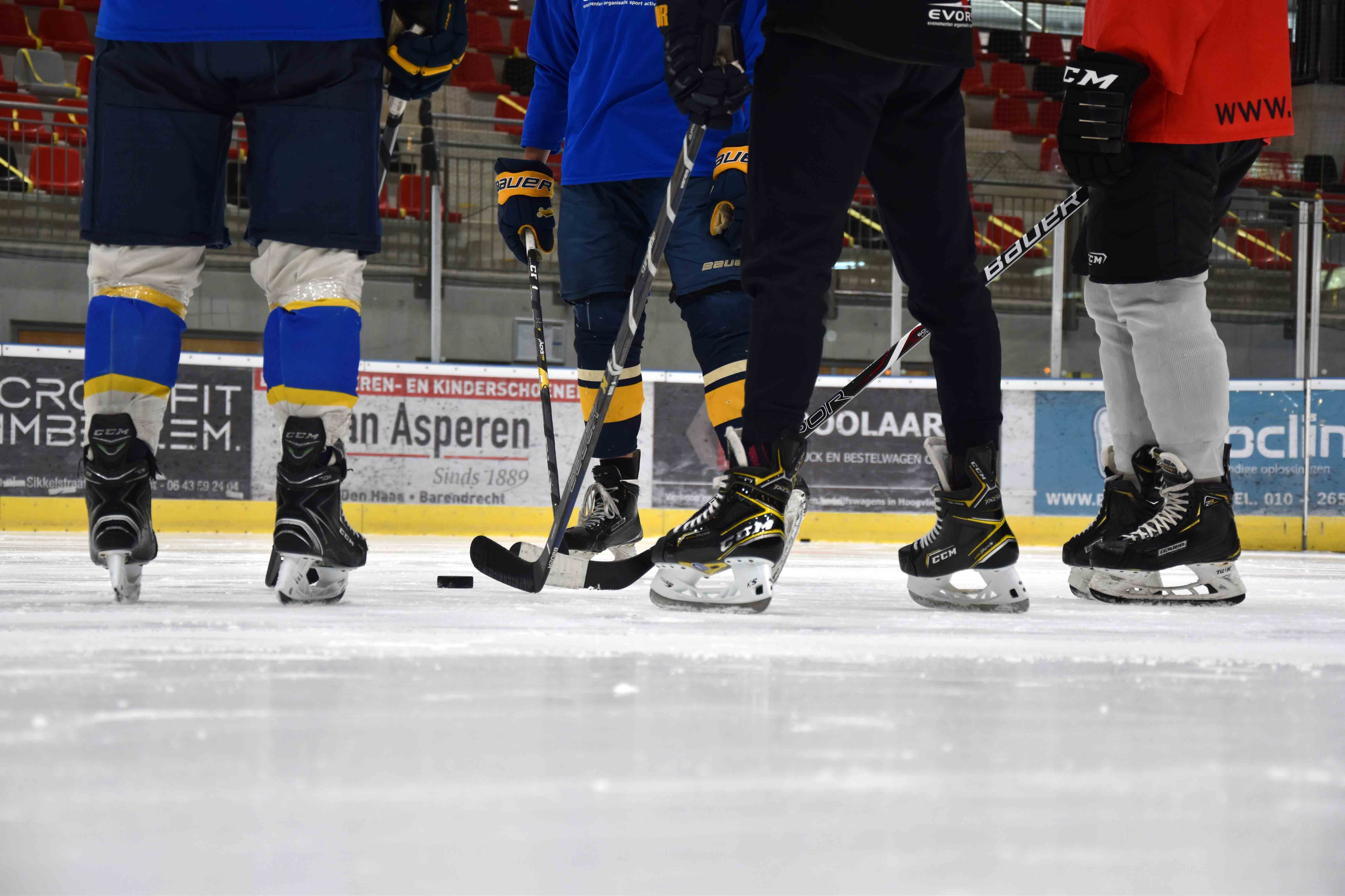 Vier mensen op het ijs met IJshockey outfit aan