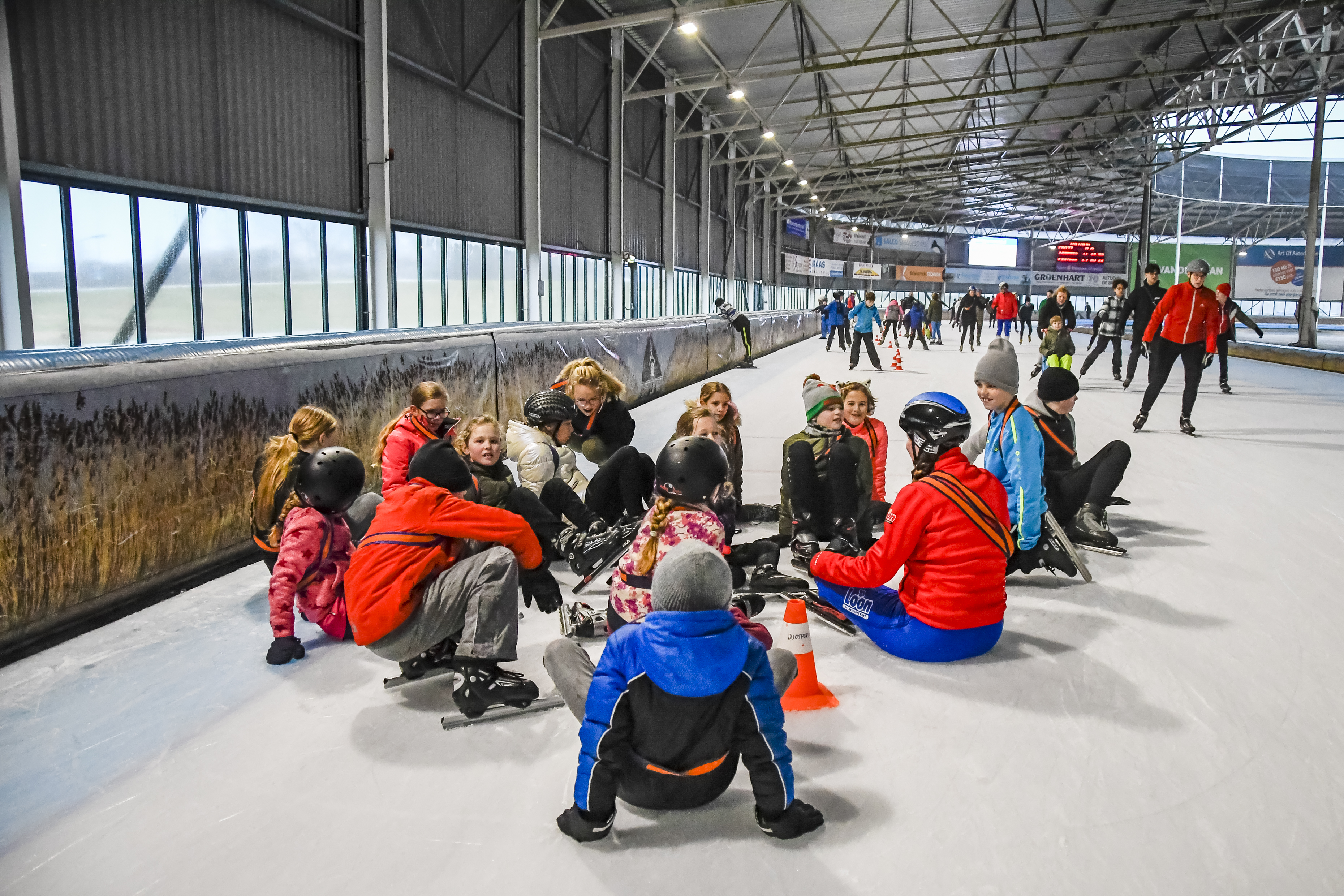 Schaatsles bij een Optisport locatie. Kinderen leren schaatsen en hebben het gezellig.