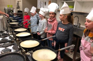 Kinderen zijn pannenkoeken aan het eten bij een zwembad van Optisport.