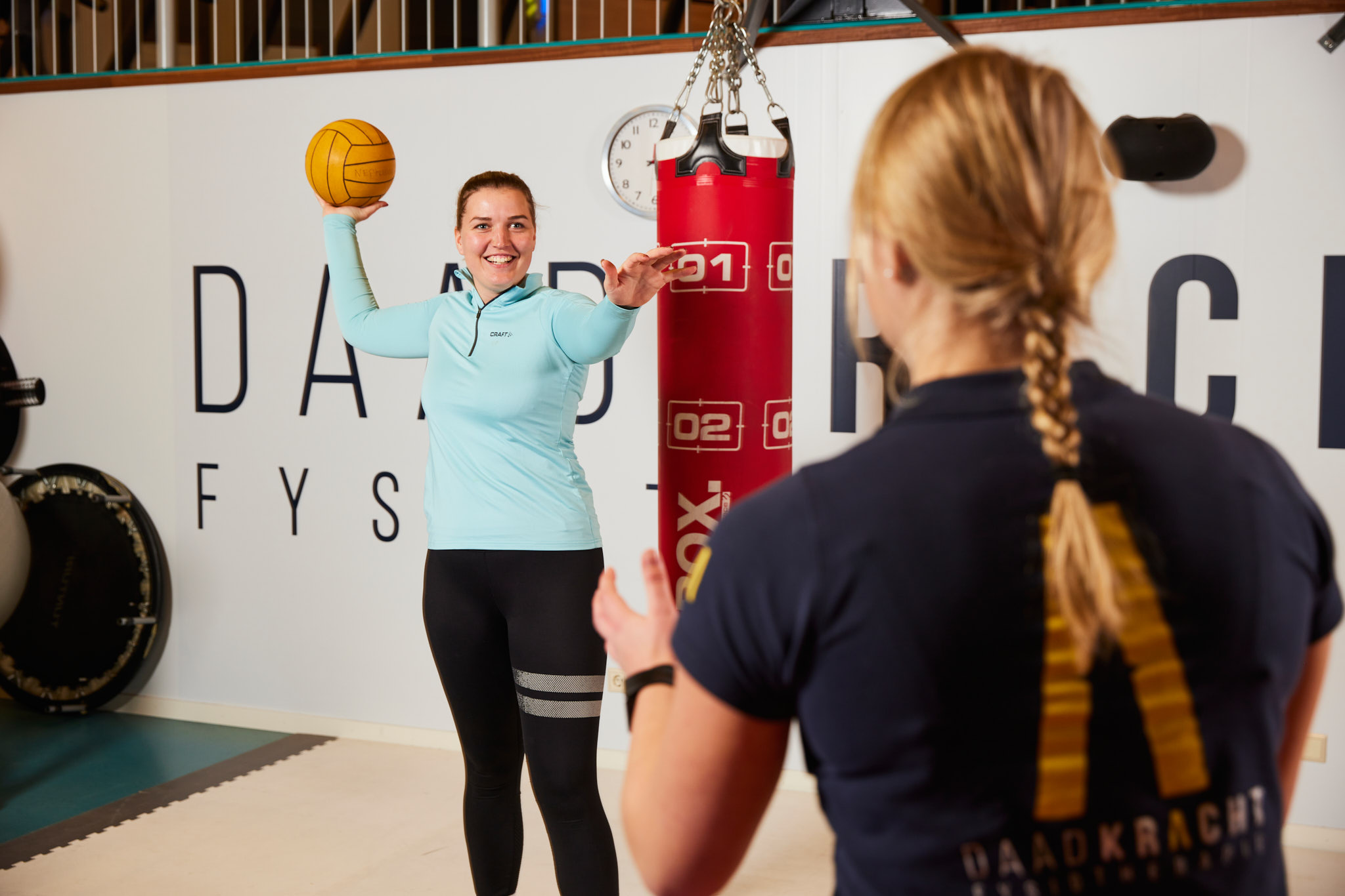 Twee vrouwen gooien bal over in sportzaal tijdens Fysiotherapie