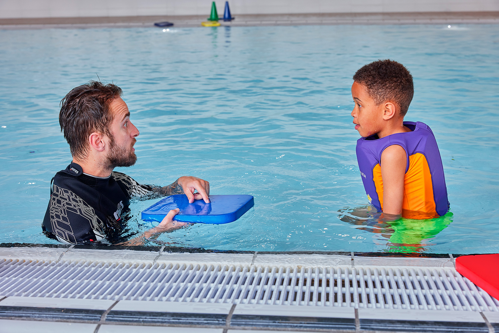 Een jongetje krijgt privé instructies tijdens het oefenen van een instructeur tijdens het Oefenuur Zwemmen in het zwembad van Optisport.