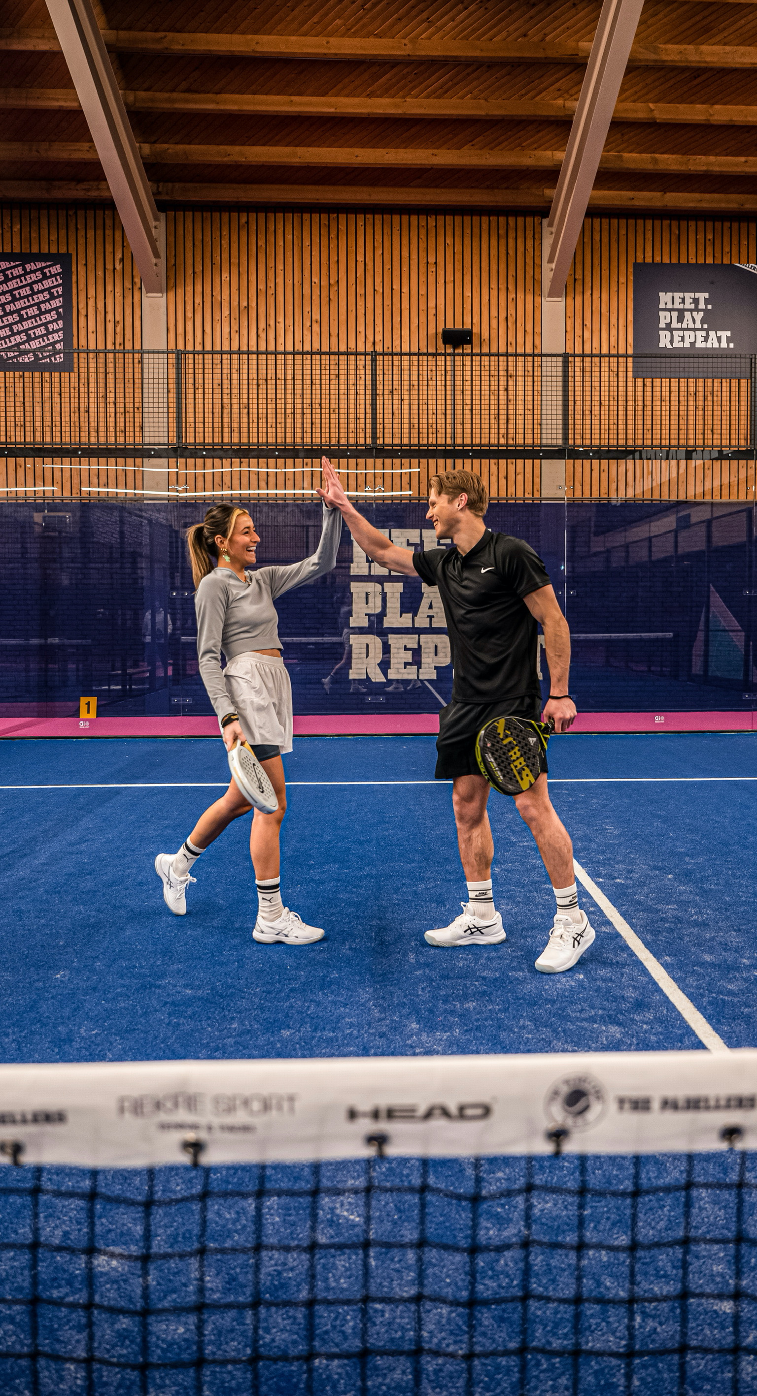 Man en vrouw zijn blij met een punt op de padelbaan tijdens het padellen.