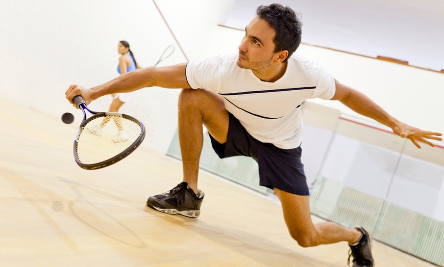 Squashen bij Optisport. Man speelt squash en is met veel plezier aan het bewegen.