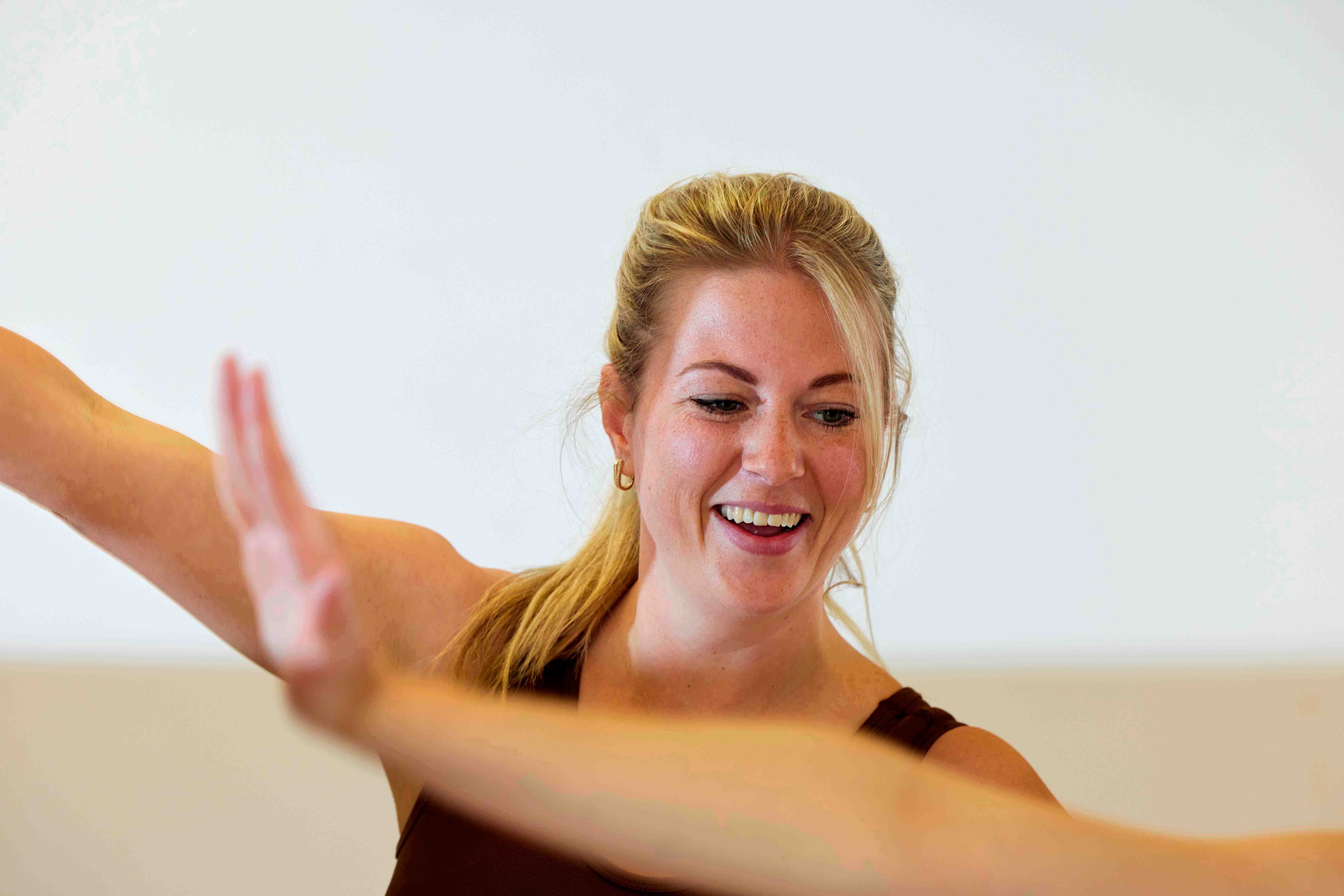 Close up van een lachende vrouw, tijdens het dansen in een les Zumba bij Optisport. 