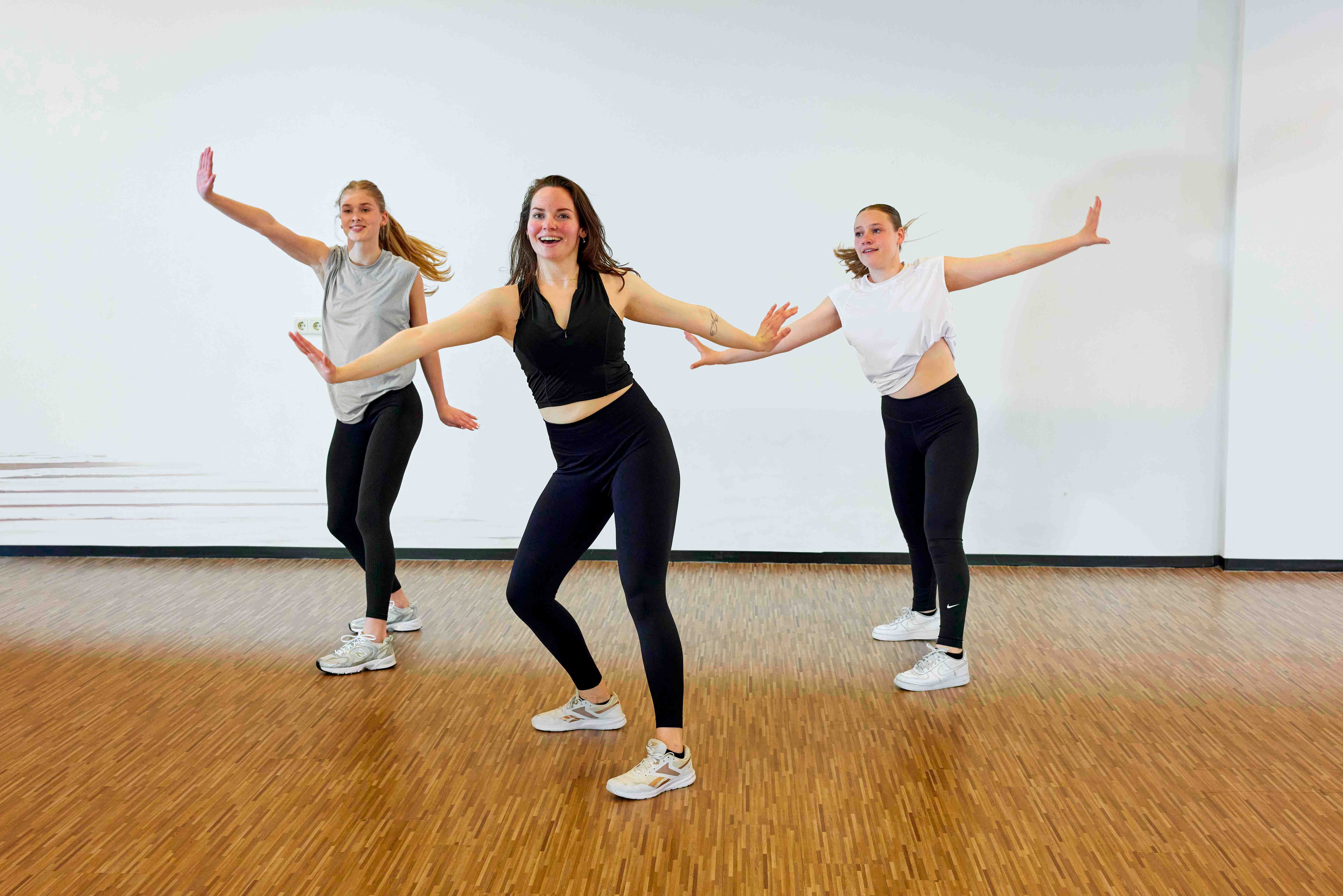 Drie jonge vrouwen tijdens de les Zumba op een van de healthclubs van Optisport; dansen is leuk! 